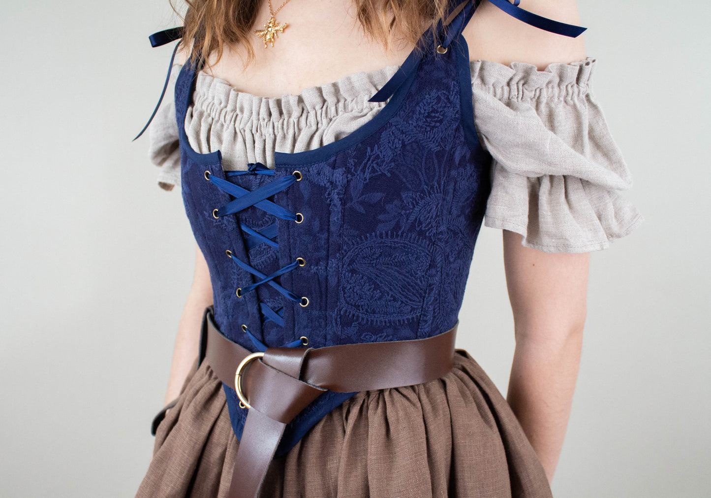 Close-up of a woman wearing a Handmade Navy Blue Embroidered Floral Corset styled with a brown belt and beige blouse