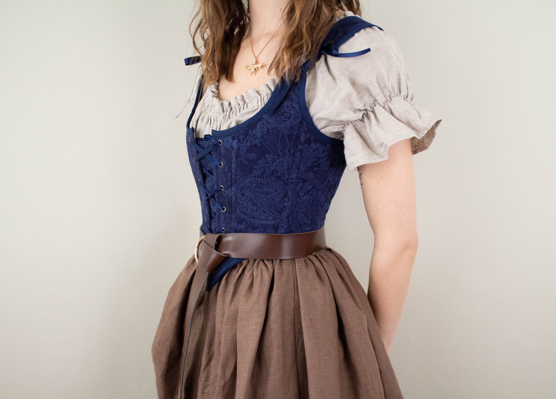 Woman wearing a Handmade Navy Blue Embroidered Floral Corset over a beige blouse and brown skirt with a belt