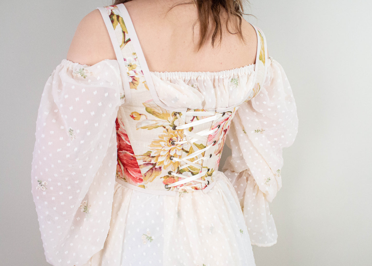 Handmade Covington Tea Rose Corset with pink floral pattern and lace-up back over puffed sheer sleeves in cottagecore style