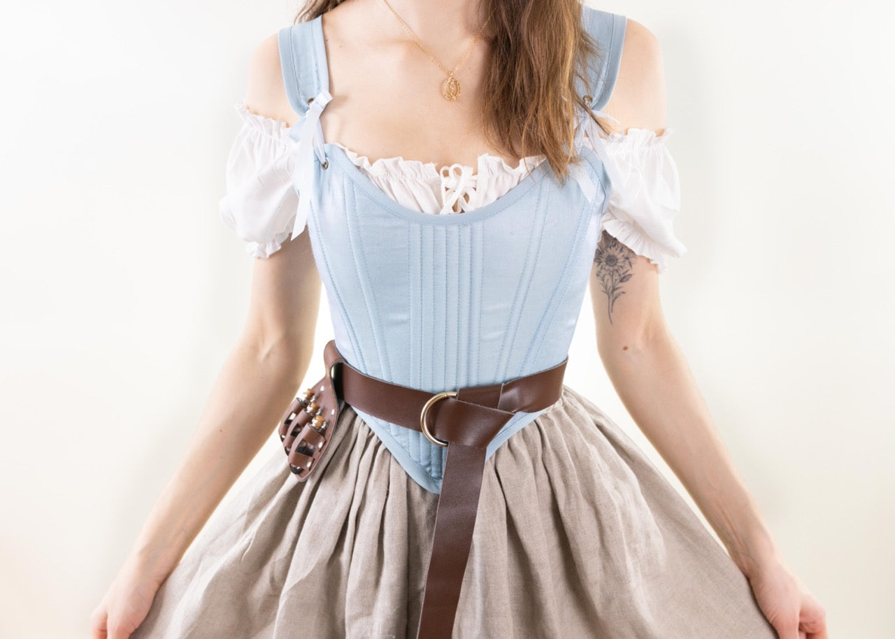 Woman wearing a Handmade Light Blue and Pink Elizabethan Stays over a white blouse and beige skirt with a brown belt