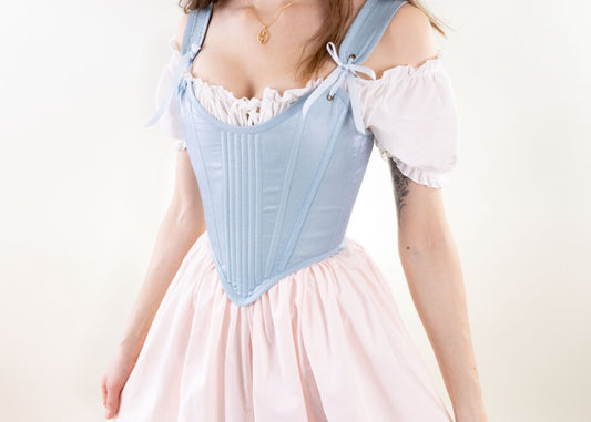 Woman wearing Handmade Light Blue and Pink Elizabethan Stays over a white blouse and pink skirt against white background