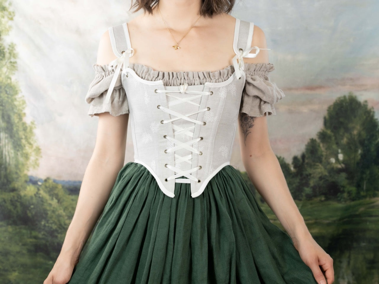 Woman wearing a Handmade Beige Fern Corset over a puffed sleeve blouse and dark green skirt in a vintage setting