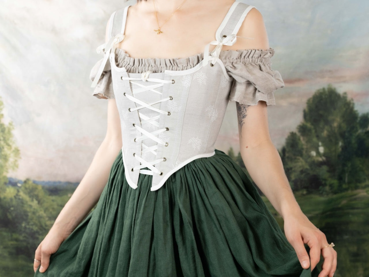 Woman wearing a Handmade Beige Fern Corset over a linen blouse with a green gathered skirt in a soft natural setting