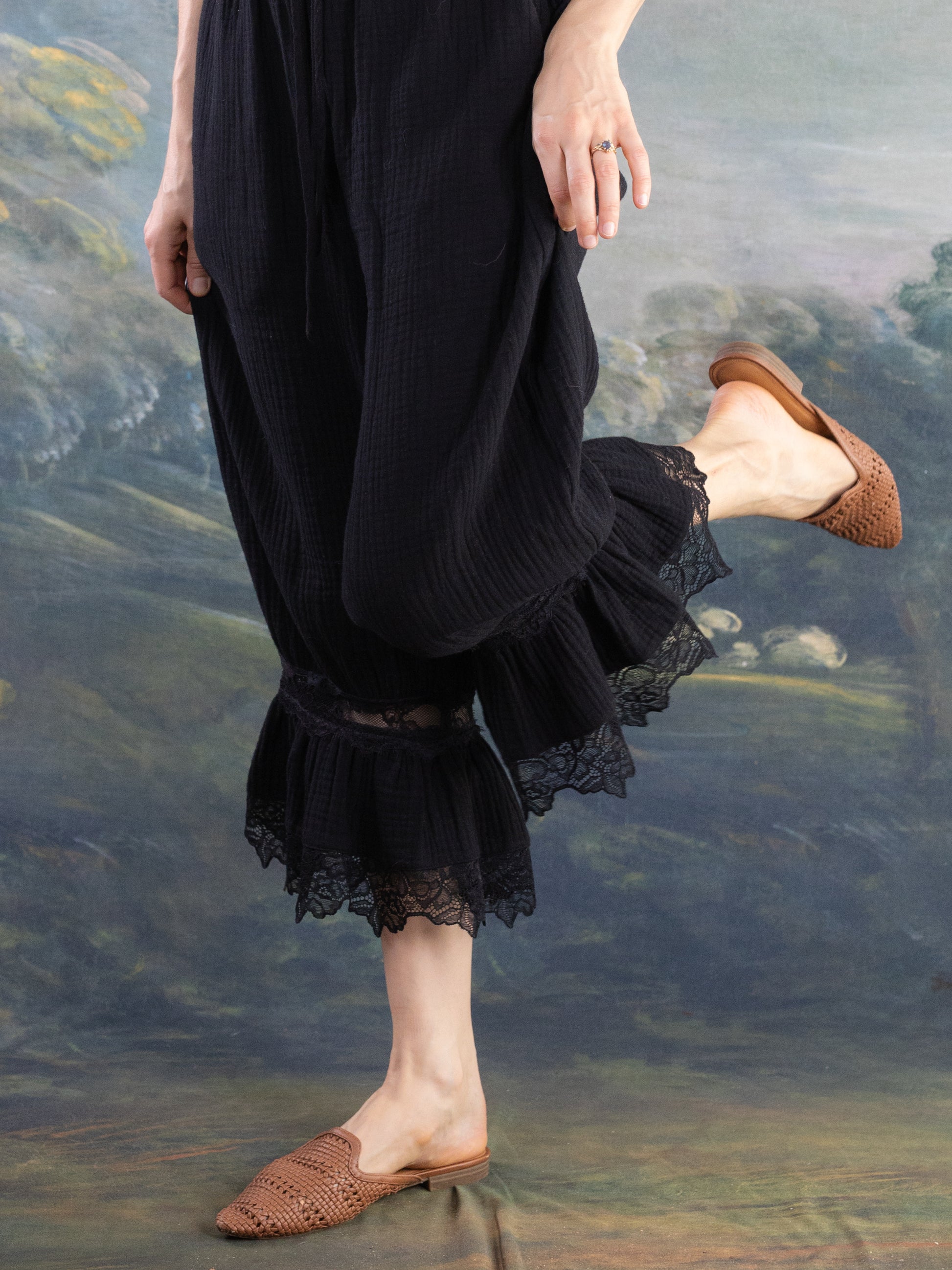 Black Bloomer Pantaloons with lace trim shown worn with brown woven slip-on shoes on a painted backdrop.