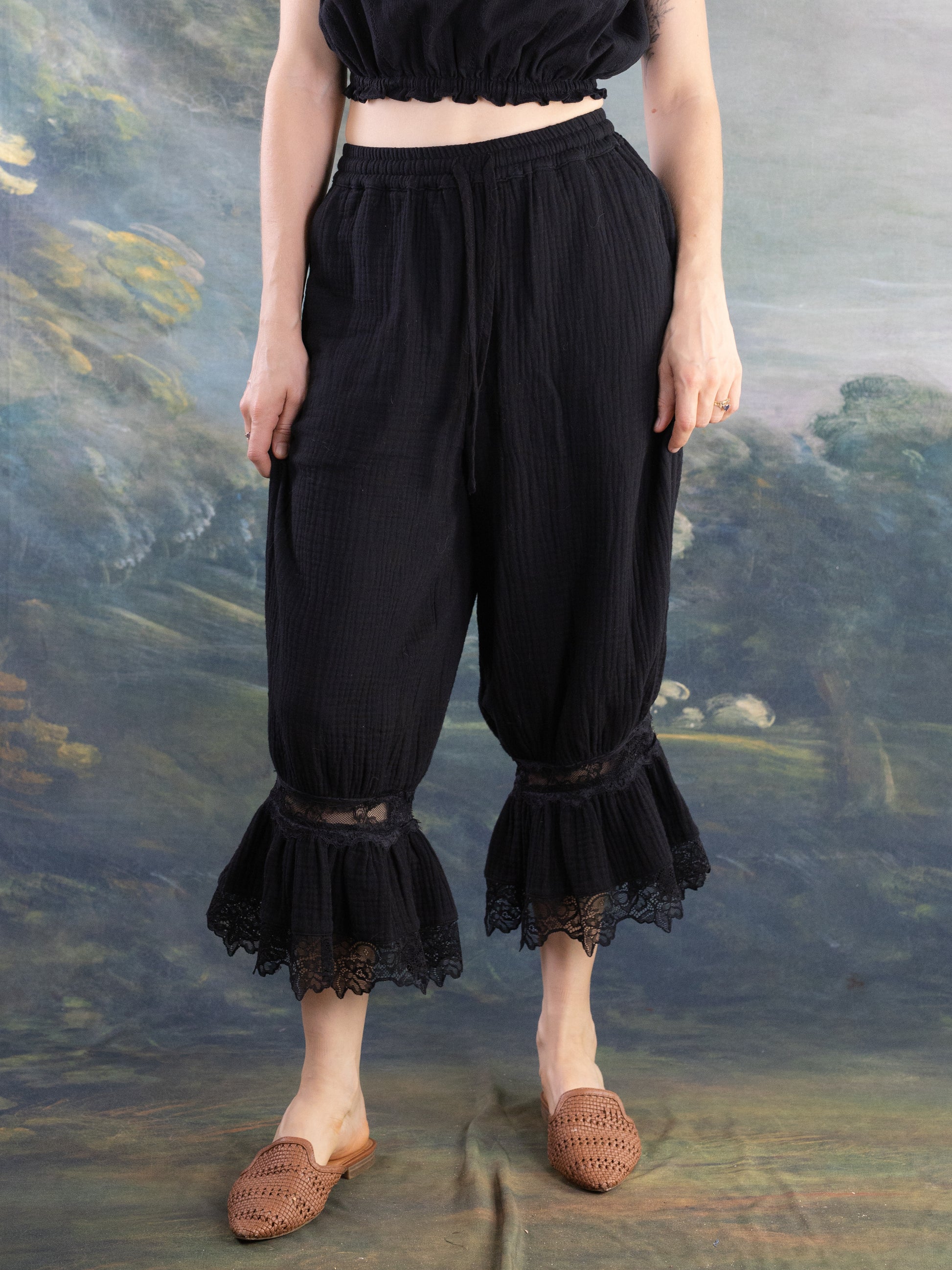 Black Bloomer Pantaloons with lace ruffle hem worn by a model standing against a muted artistic background