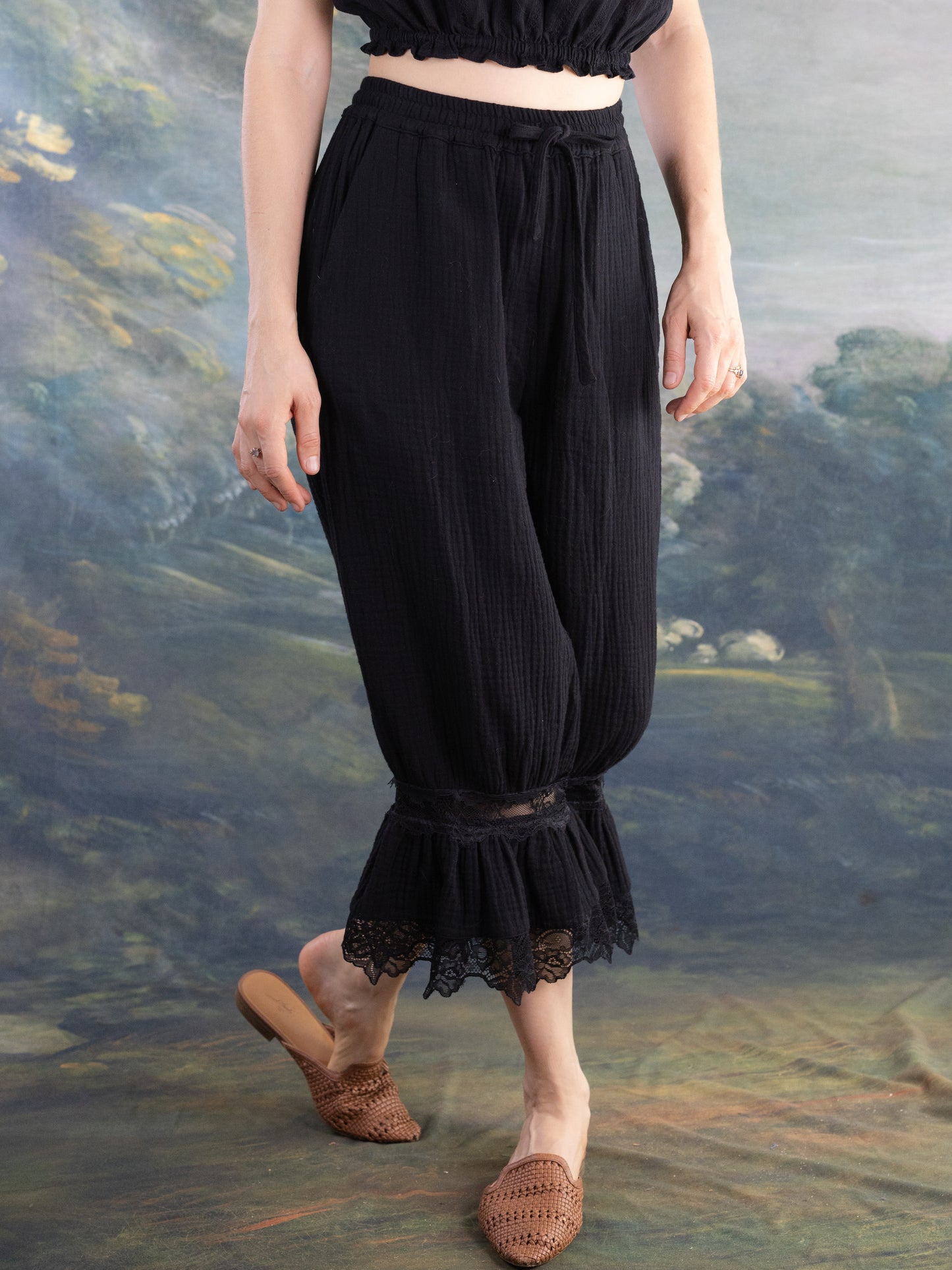 Woman wearing black Bloomer Pantaloons with lace trim at the cuffs and a tied waistband standing barefoot.