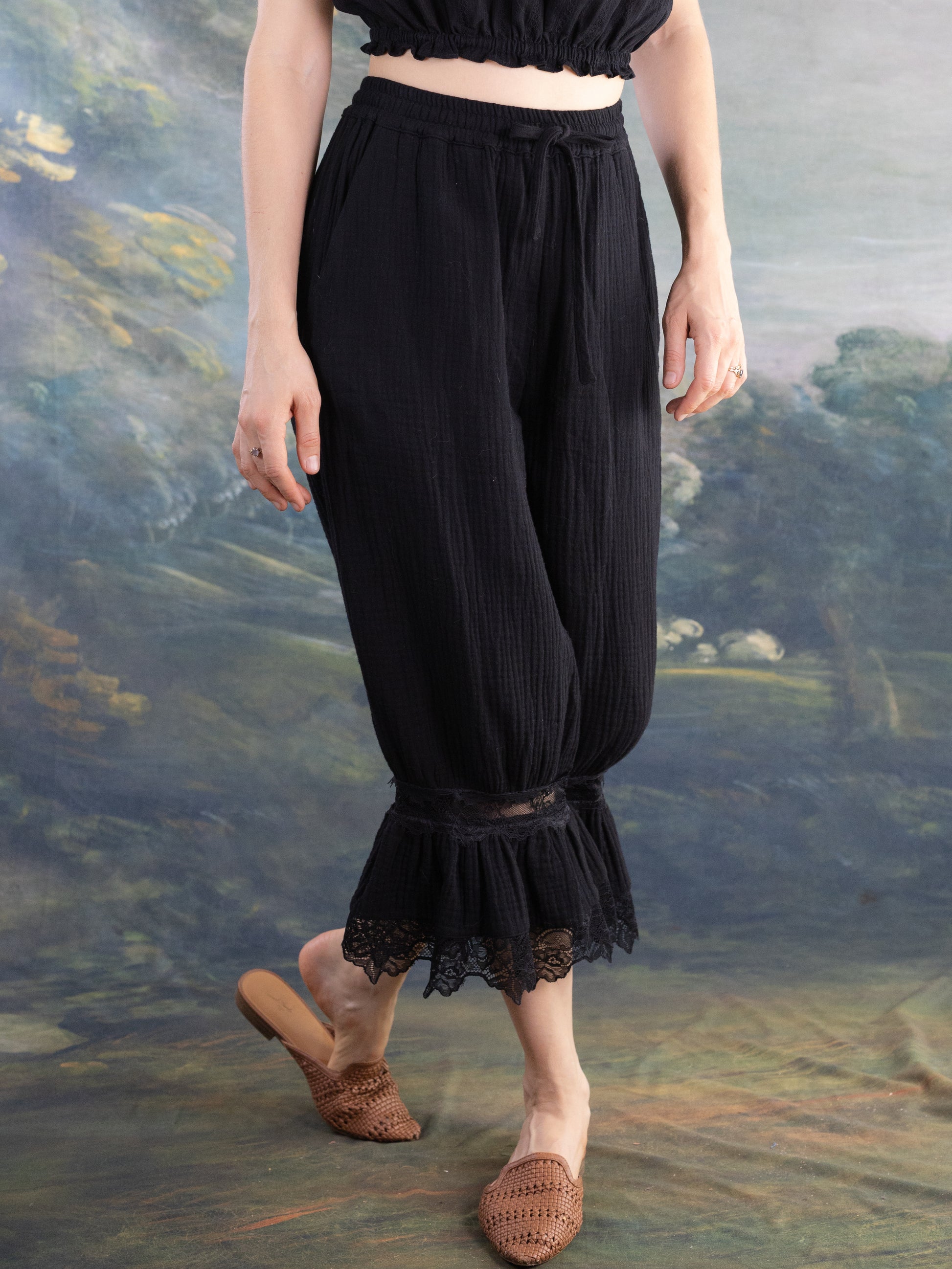 Woman wearing black Bloomer Pantaloons with lace trim at the cuffs and a tied waistband standing barefoot.