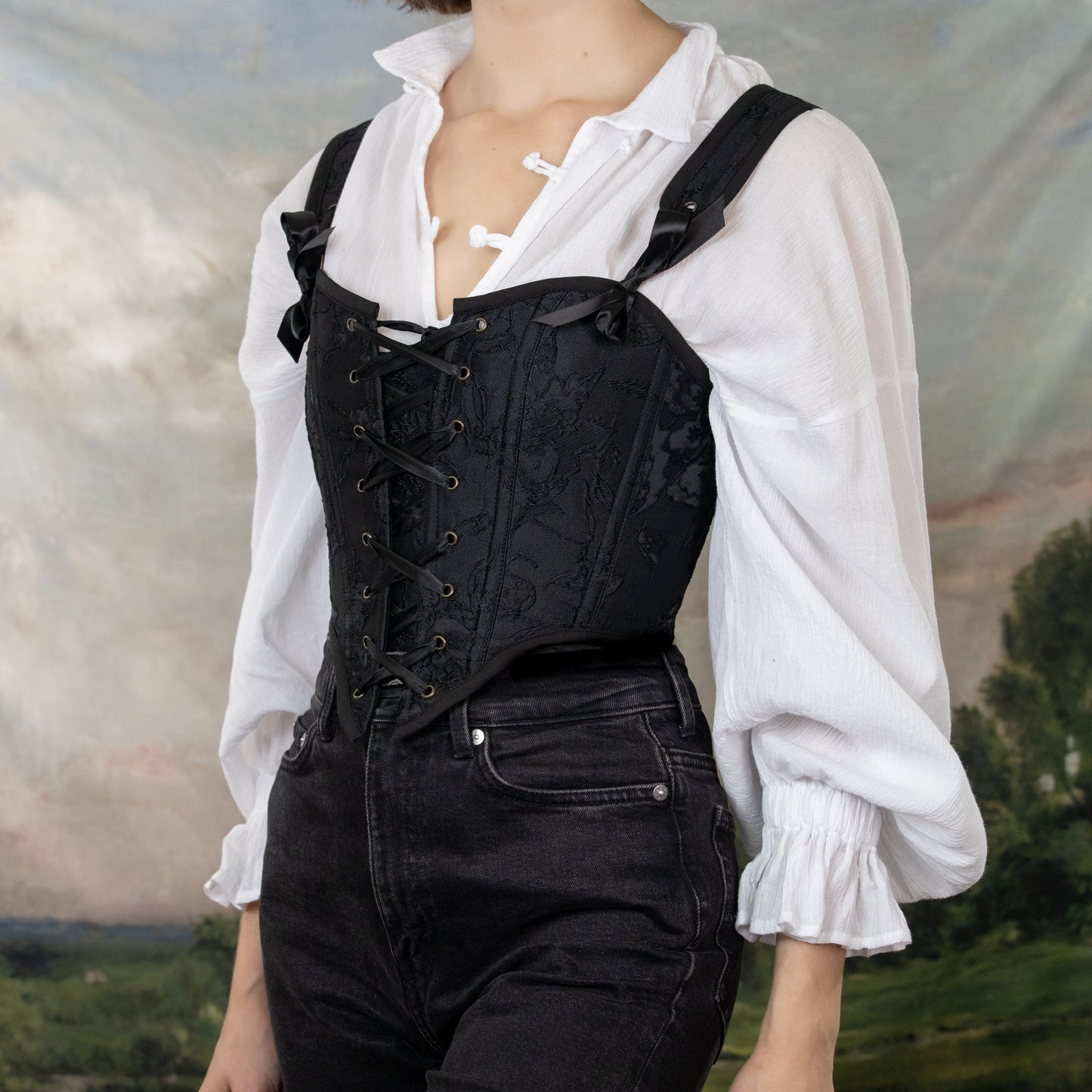 model wearing vampire costume including a white long sleeve shirt with billowing sleeves and a black jacquard corset