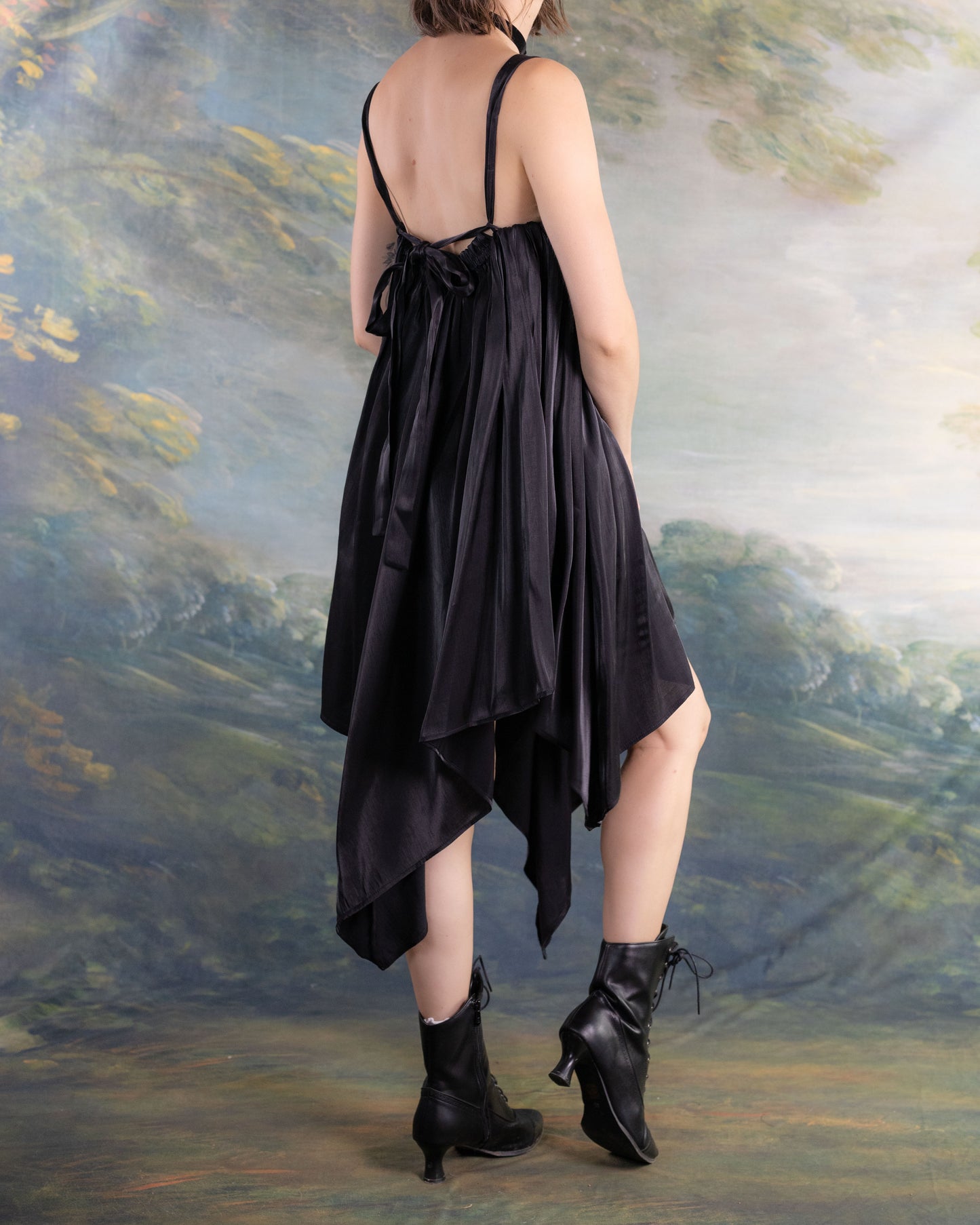 Back view of a model wearing the Black Flutter Fairy Dress with handkerchief hem and strappy back design