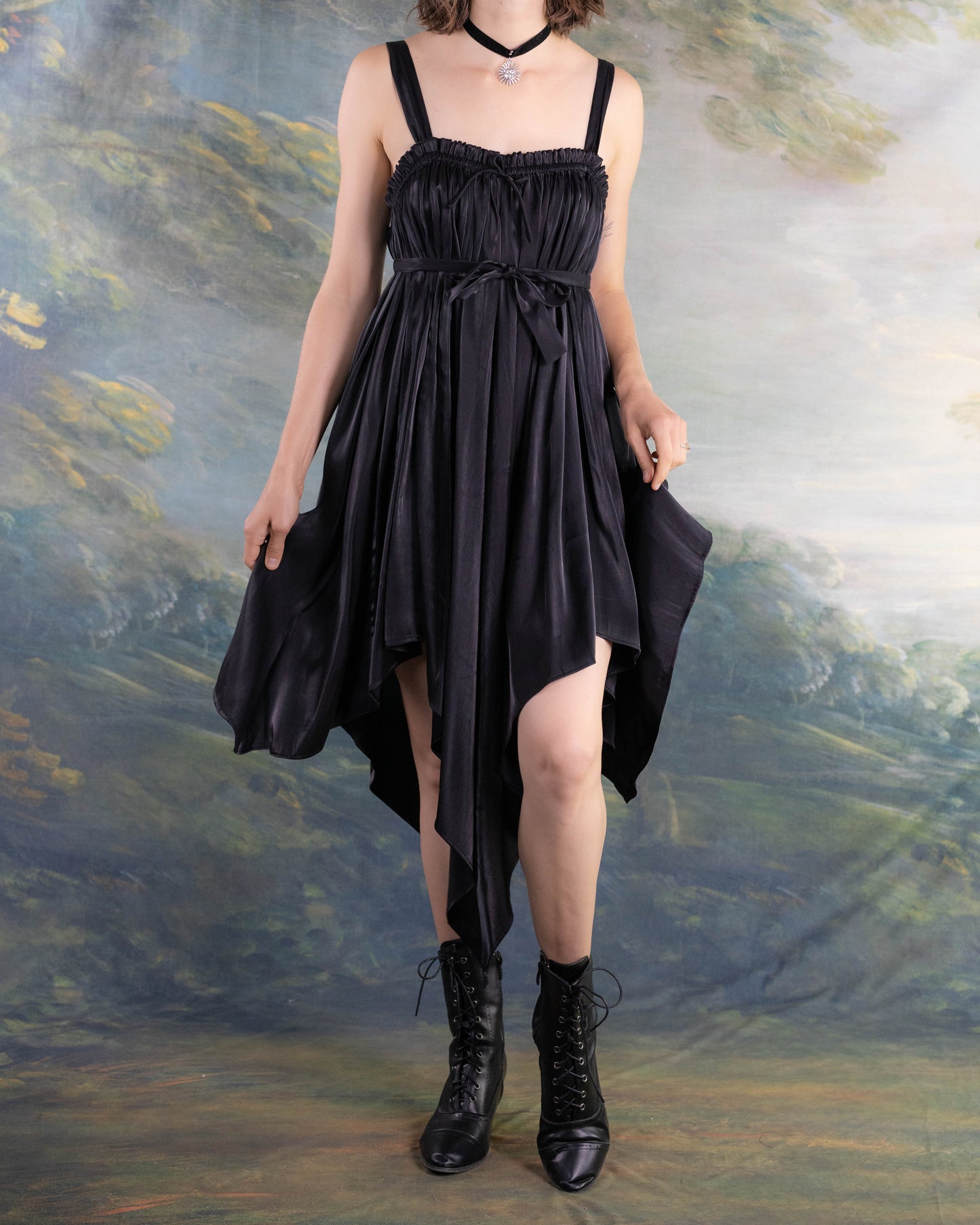 Black Flutter Fairy Dress with handkerchief hem and satin fabric worn with lace-up boots against painterly backdrop
