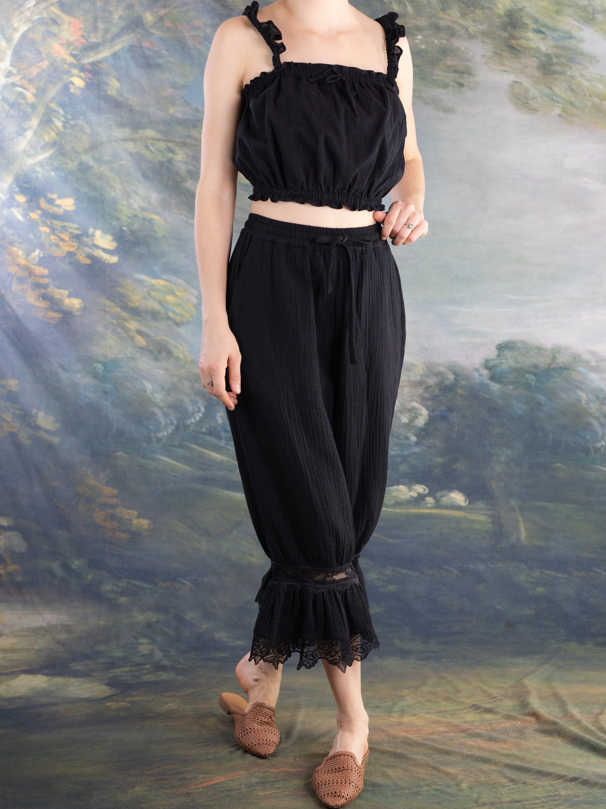 Model wearing Lacey Chemisette Tank black cropped top with ruffled straps and elastic hem for layering or standalone style