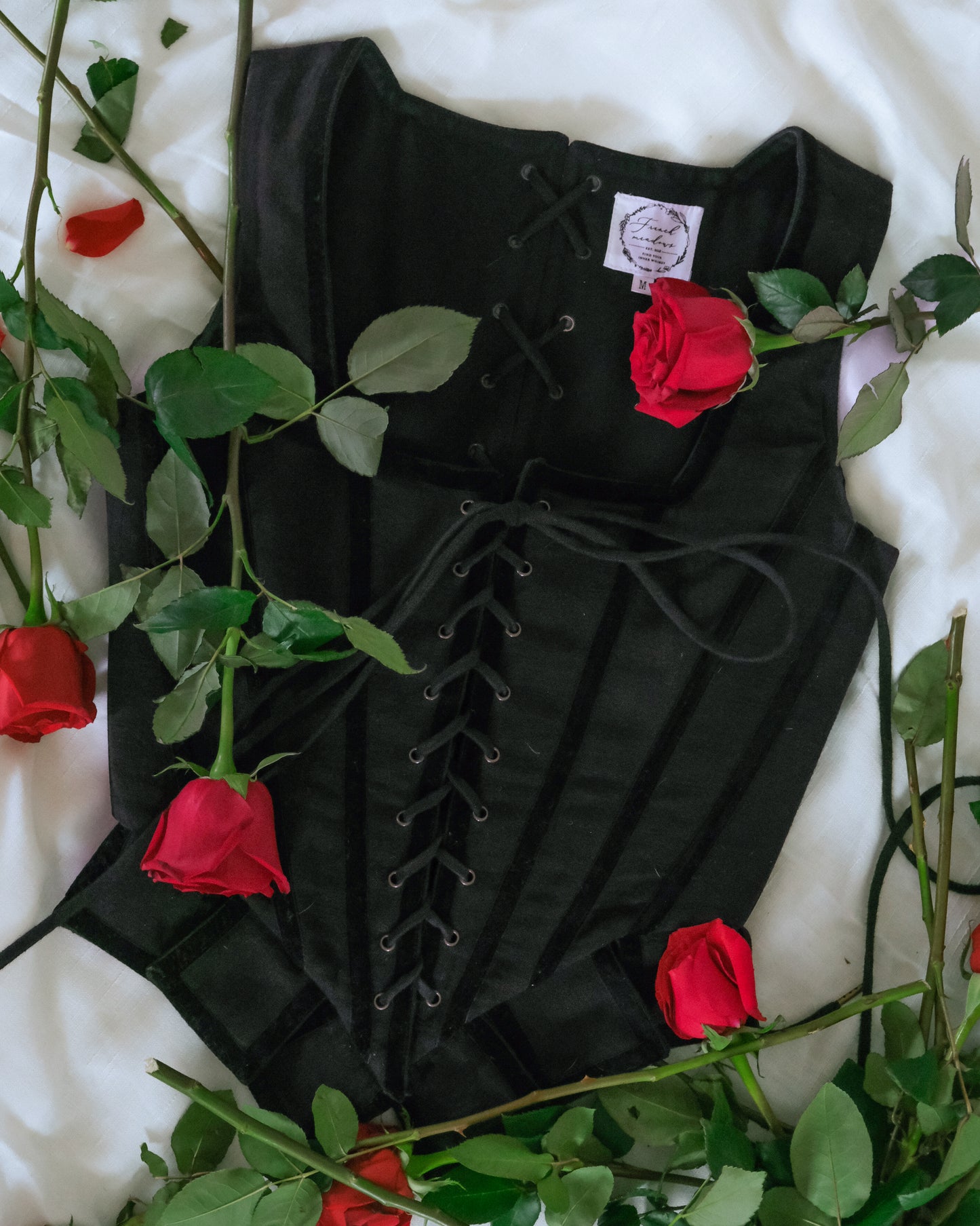 Black Pirate Doublet with lace-up front detail surrounded by red roses on a white background