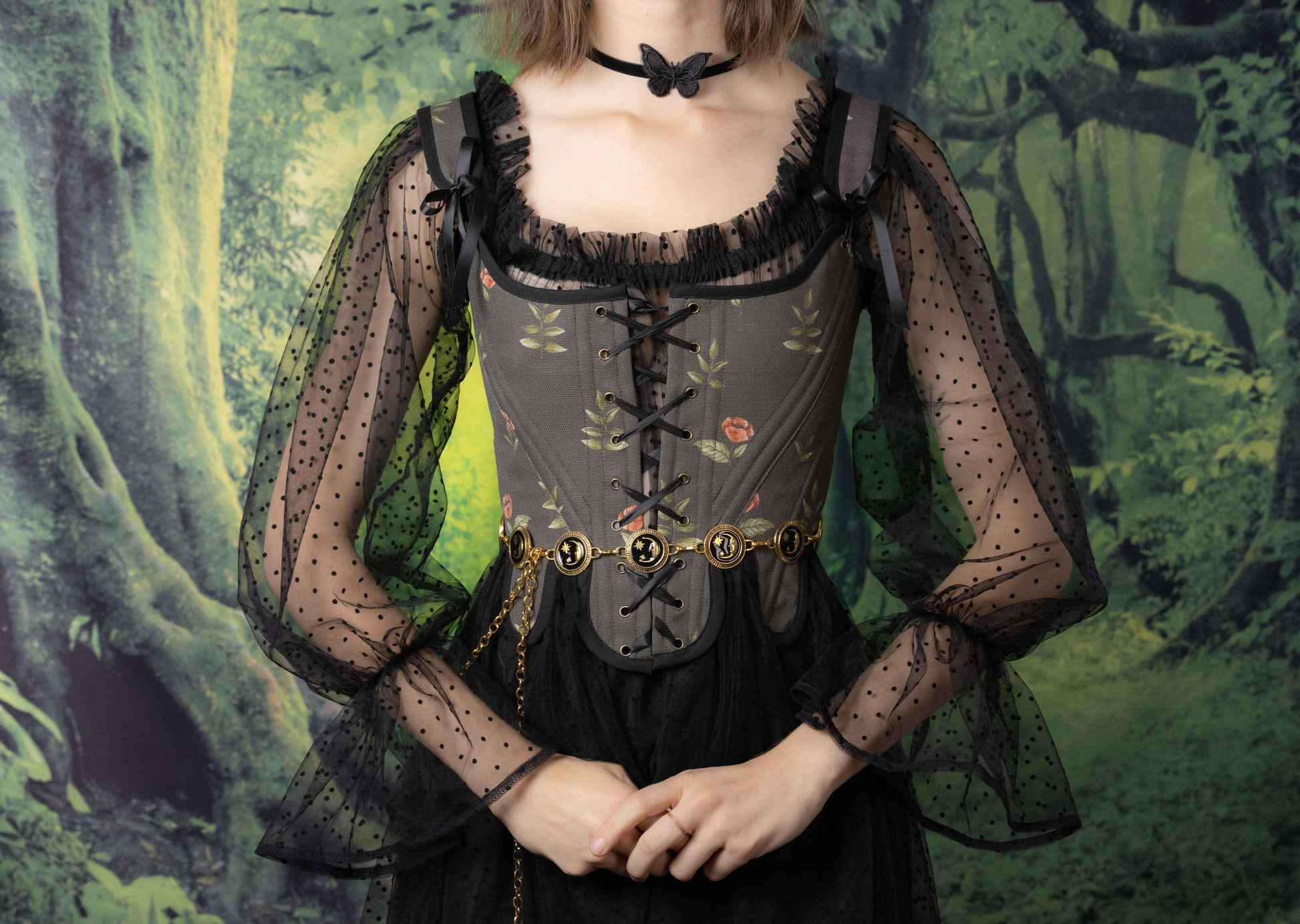 A model wearing Handmade Black Rose Floral 18th Century Stays with sheer black sleeves and a butterfly choker.