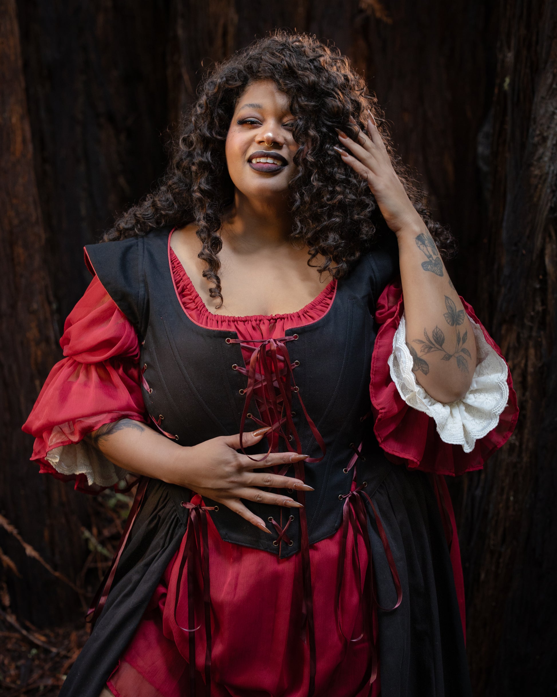 woman with curly hair wearing a Black Vampire Slayer Corset Dress with red and white layered sleeves outdoors