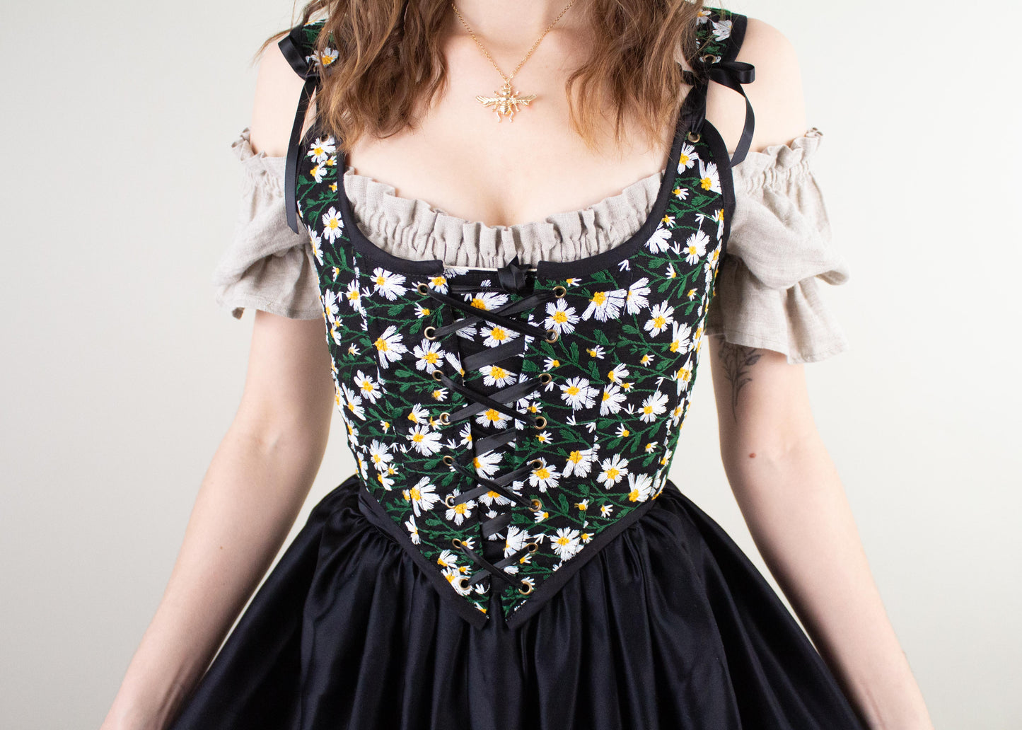 Woman wearing Handmade Black Embroidered Floral Daisies corset with lace-up front over beige blouse and black skirt