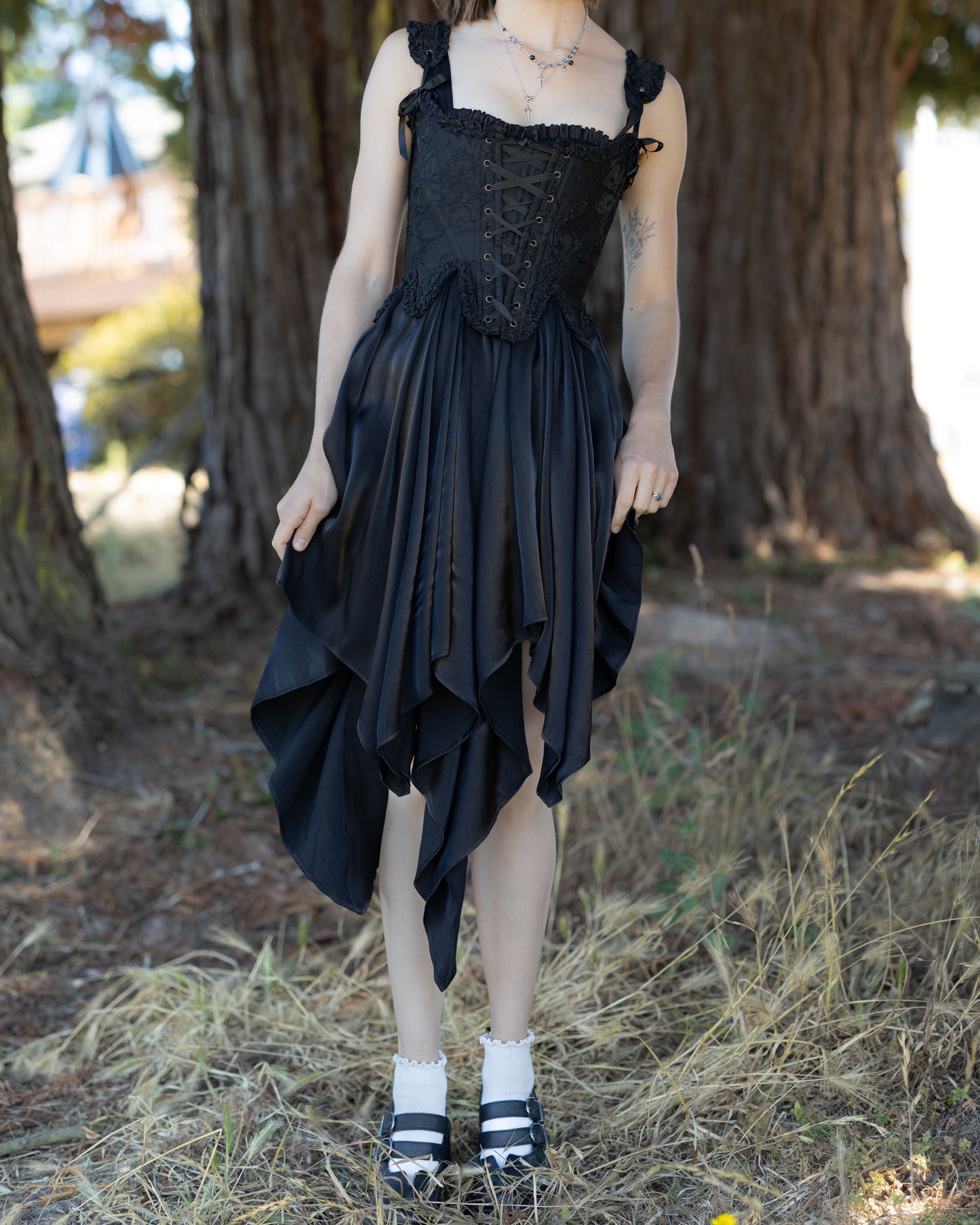 Black Flutter Fairy Dress worn outdoors with handkerchief hem and lace-up bodice details in natural light.