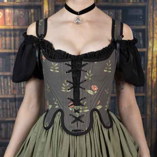 Woman wearing Handmade Black Rose Floral 18th Century Stays with floral pattern and black lace-up front over a green skirt