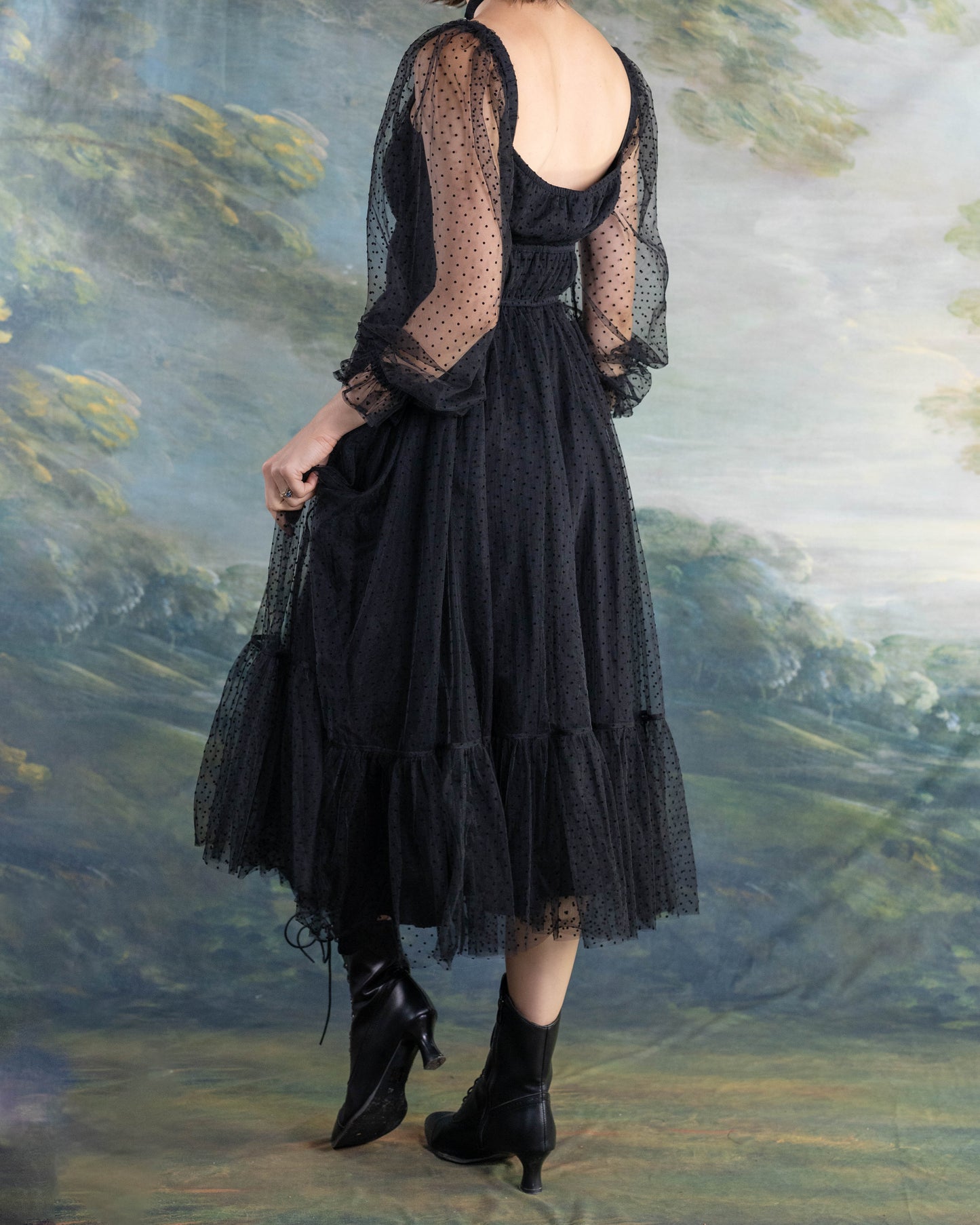 Woman wearing a Black Tulle Dot Dress with sheer long sleeves and ruffled hem in an artistic outdoor setting