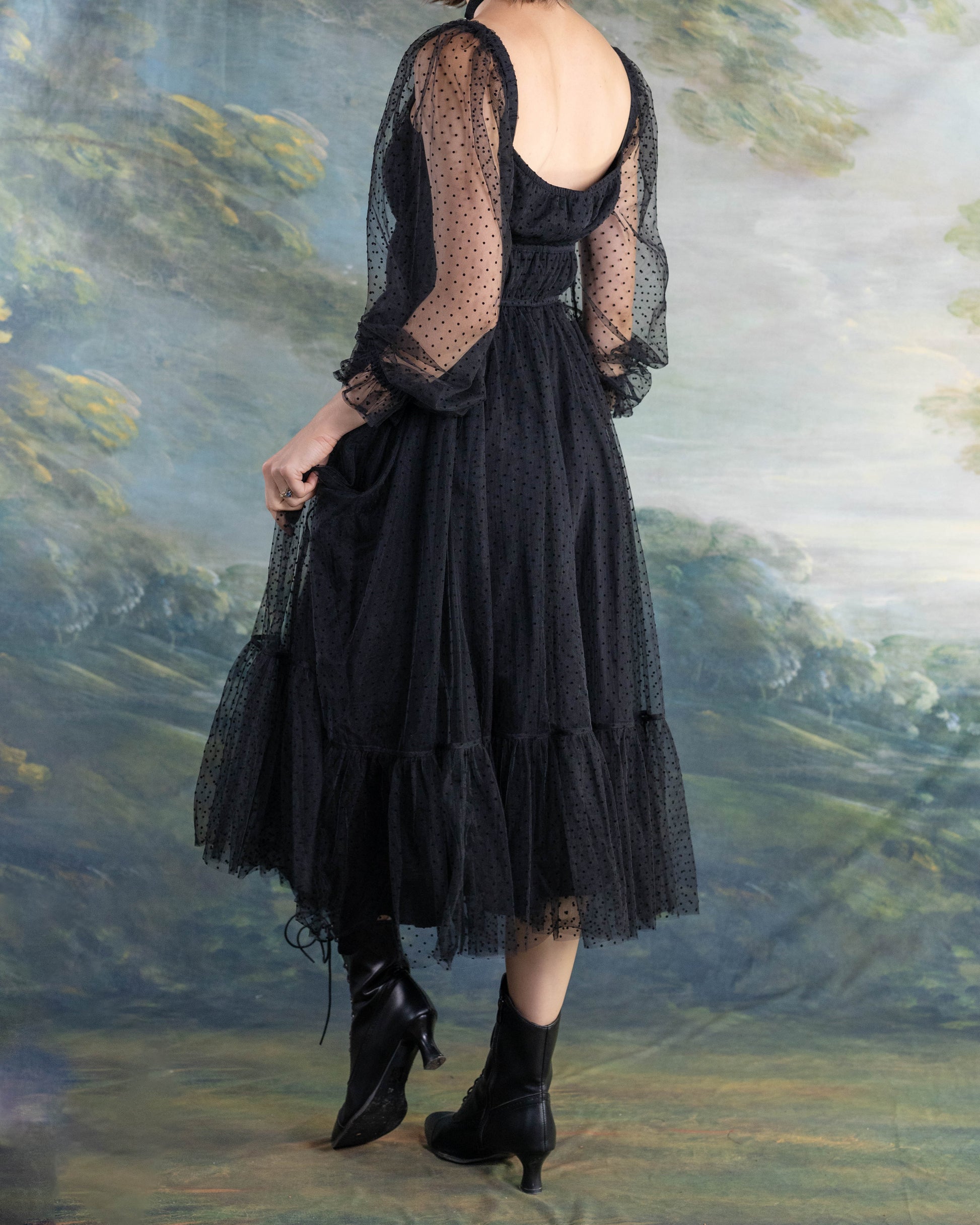 Woman wearing a Black Tulle Dot Dress with sheer long sleeves and ruffled hem in an artistic outdoor setting