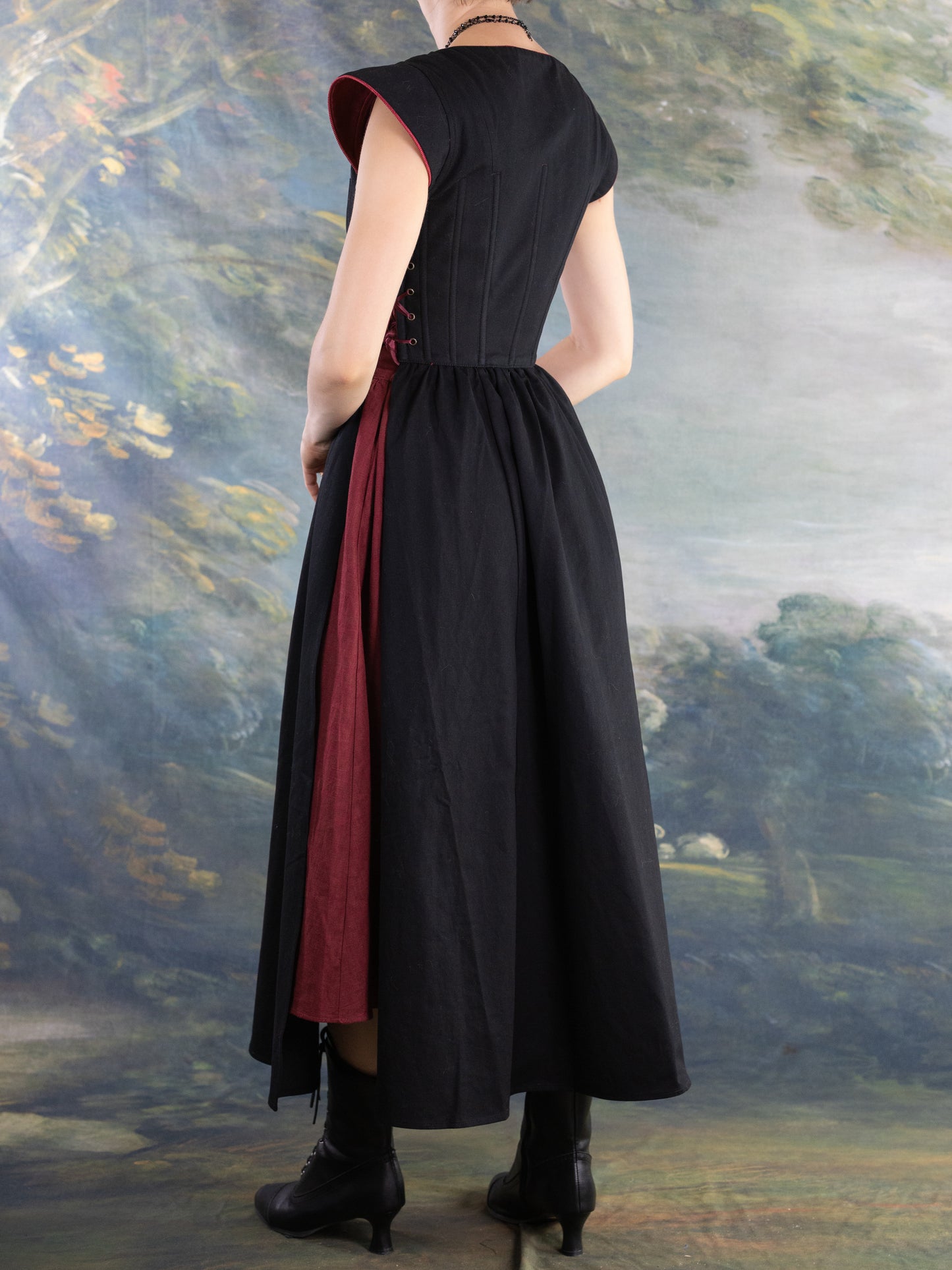 Back view of model wearing Black Vampire Slayer Corset Dress with adjustable structured bodice and dark red inner panel
