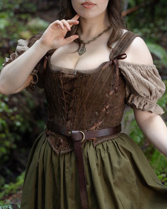 Brown Princess Stays corset shown in portrait with lace-up front, off-shoulder sleeves, and attached leather belt detail.
