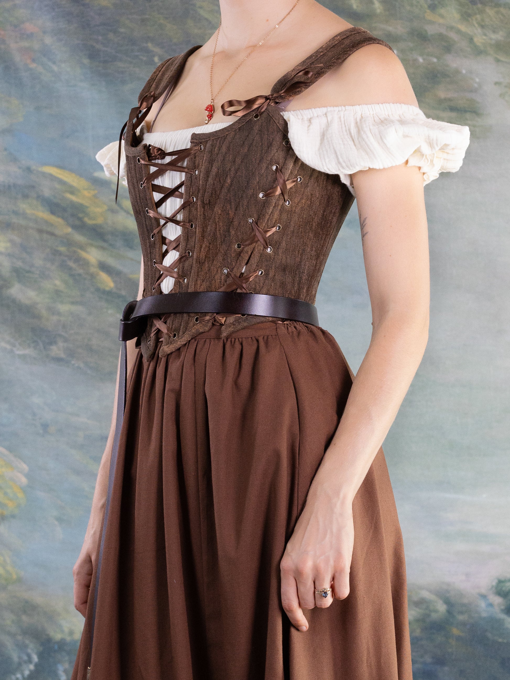 Close-up of a woman wearing Brown Princess Stays brown adjustable corset with white off-shoulder blouse and matching skirt
