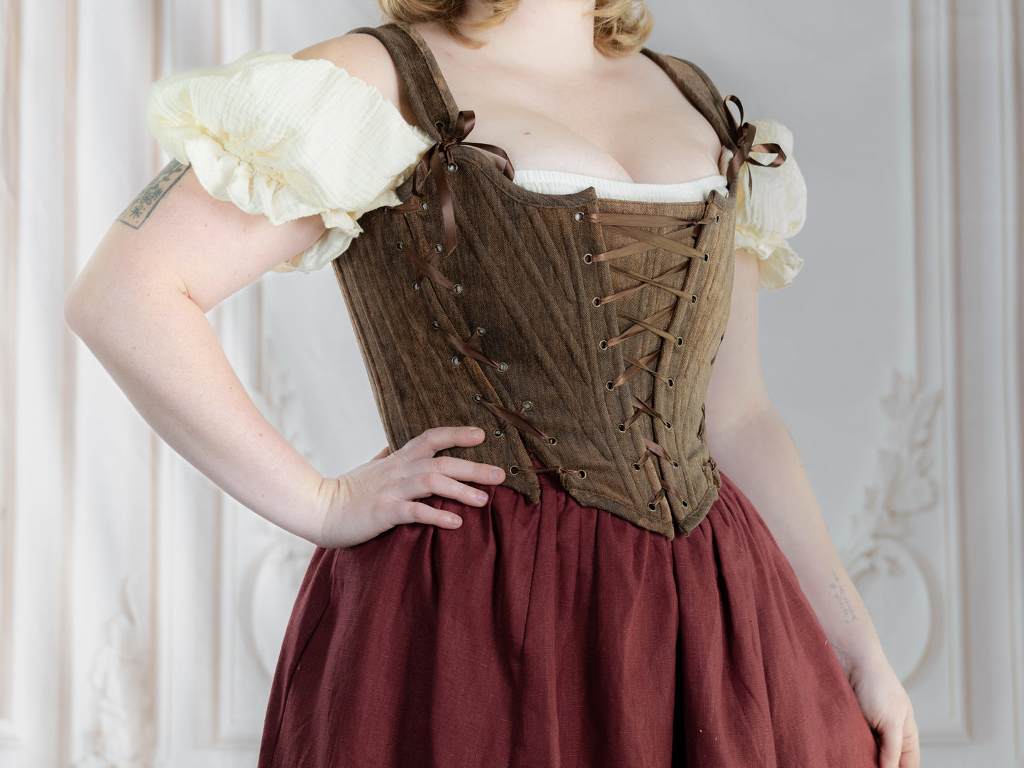 Woman wearing a brown corset styled as Brown Princess Stays paired with a cream blouse and burgundy skirt