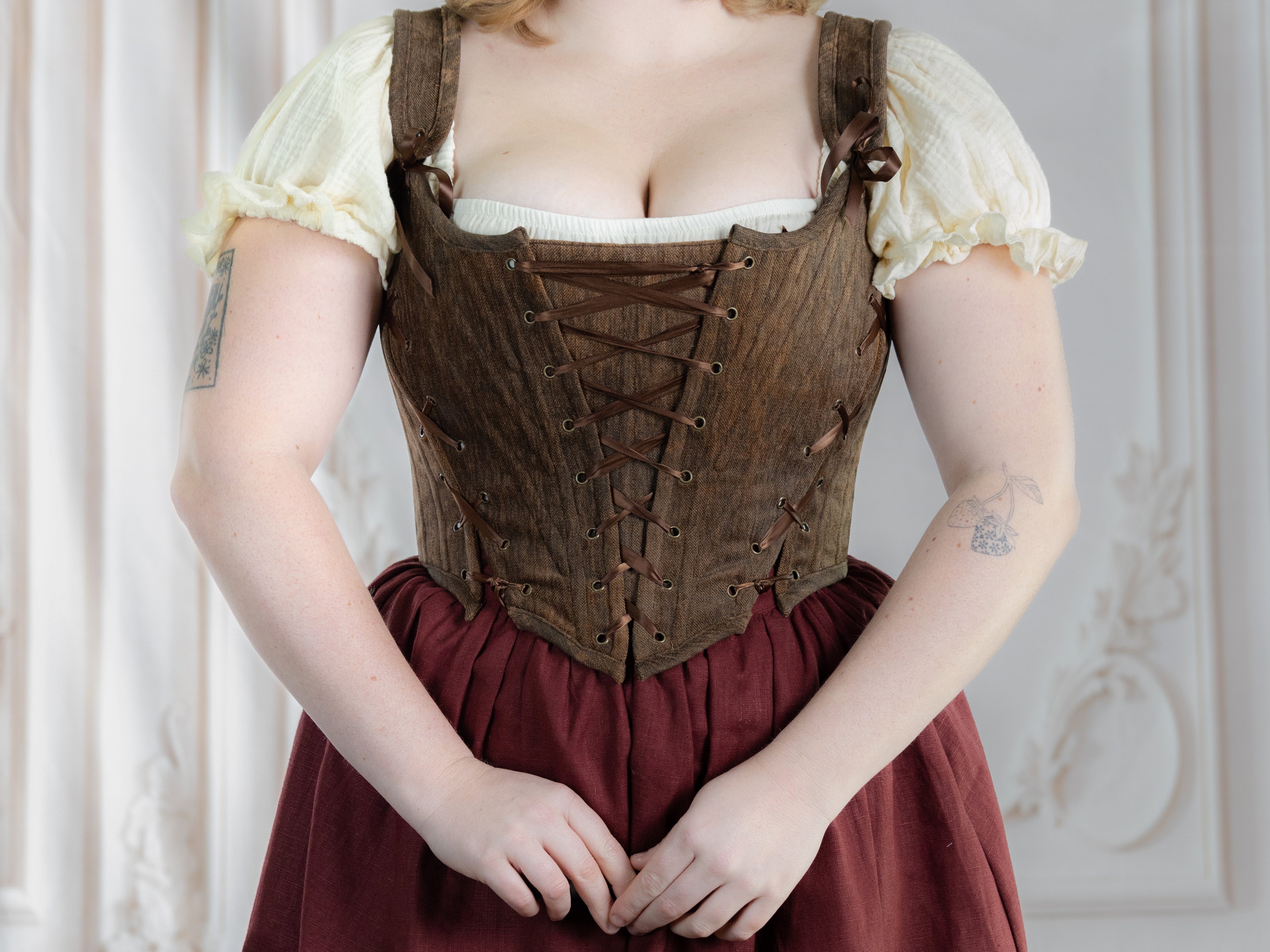 Close-up of a woman wearing a brown corset styled as Brown Princess Stays with puffed sleeves and laced front