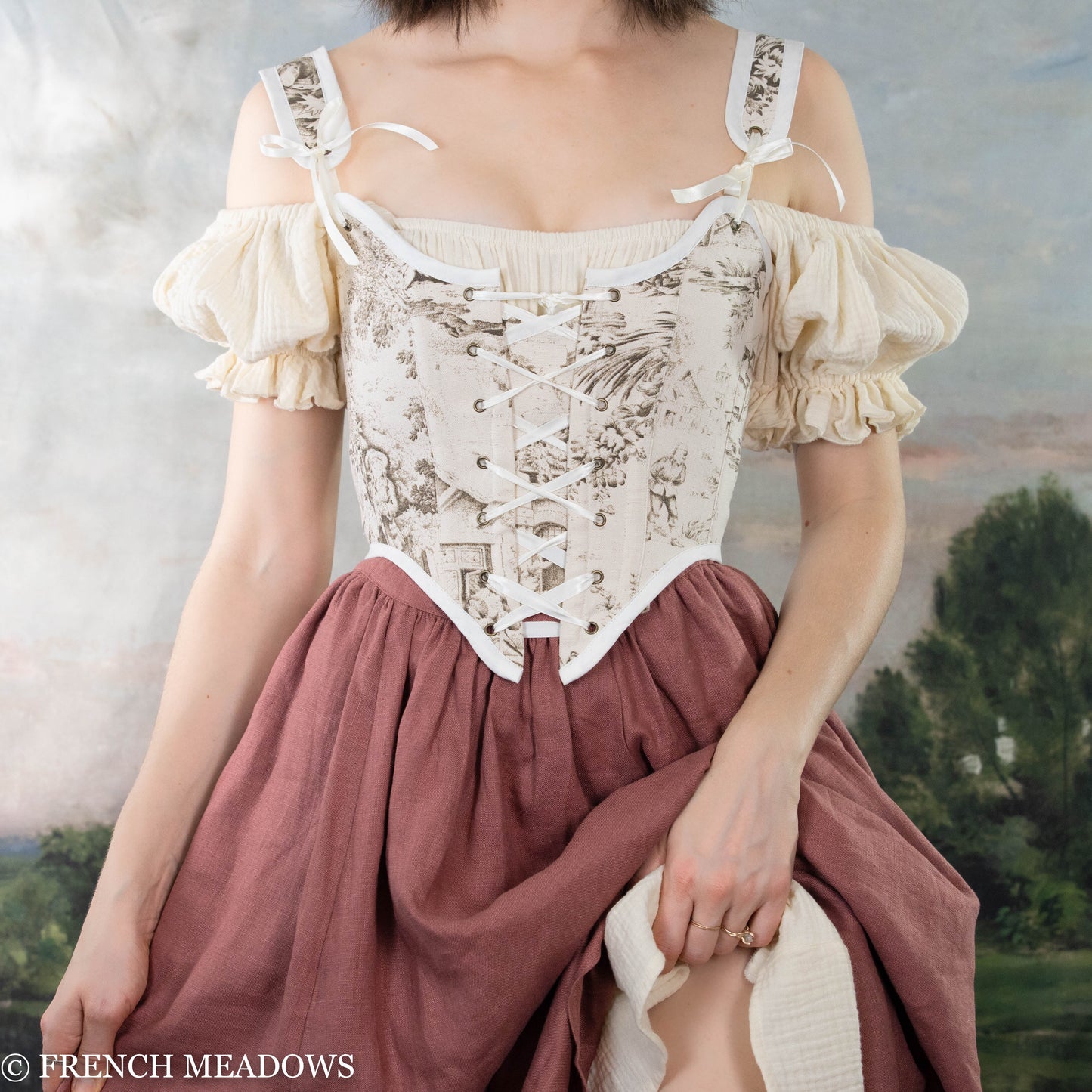 model wearing brown renaissance bodice with a cream colored chemise worn off the shoulders