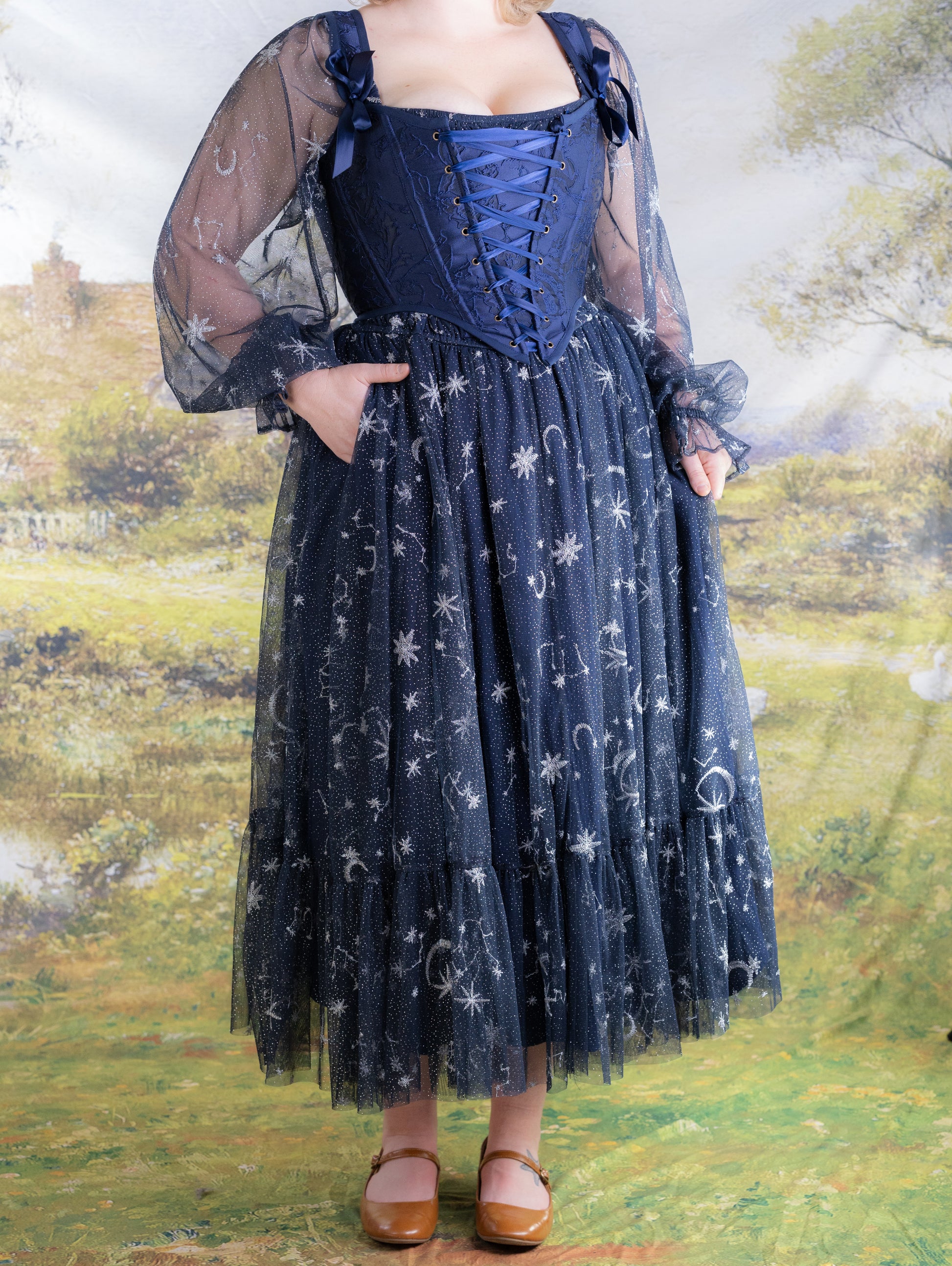 Woman wearing navy blue Celestial Tulle Dress with celestial patterns standing outdoors on grass background