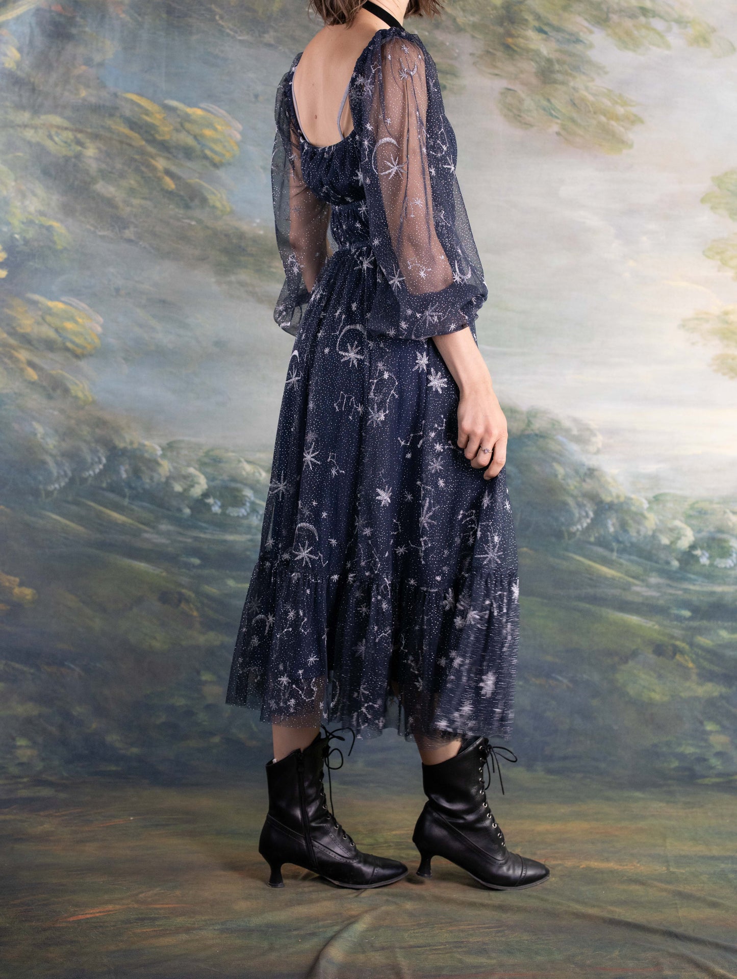 Celestial Tulle Dress with sheer navy fabric, star patterns, and puffed sleeves paired with black lace-up boots.