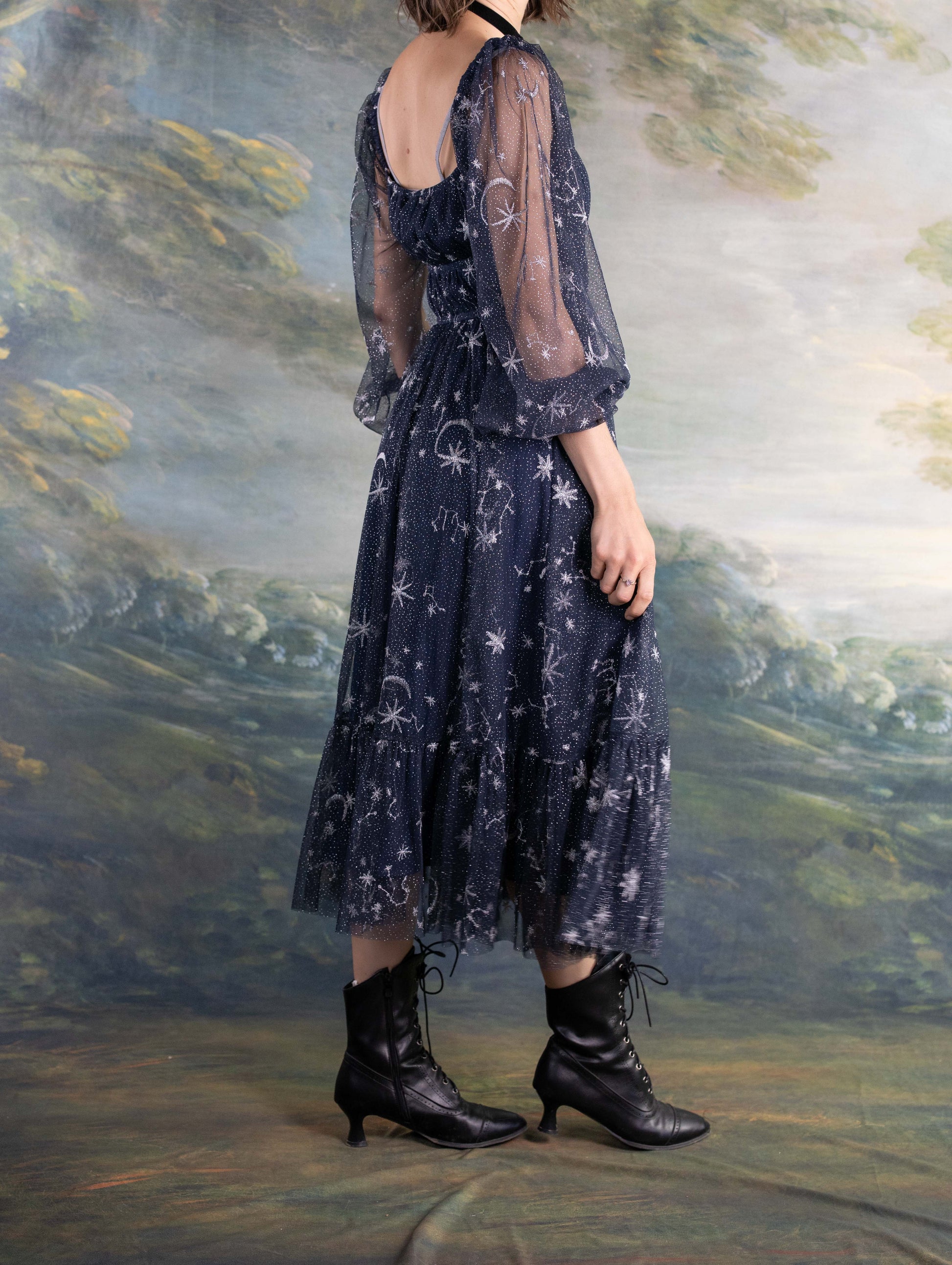 Celestial Tulle Dress with sheer navy fabric, star patterns, and puffed sleeves paired with black lace-up boots.