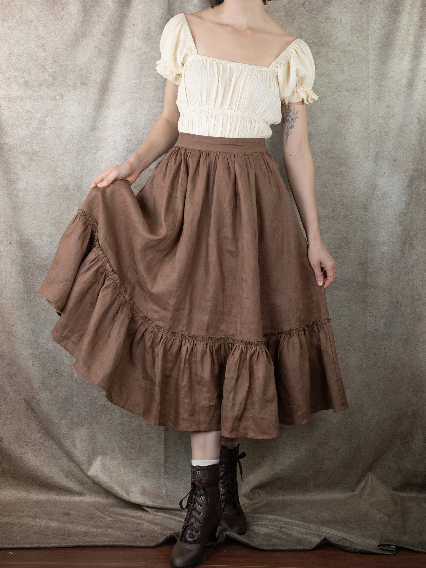 woman wearing a long ruffled midi skirt with the skirt hem picked up to show fullness