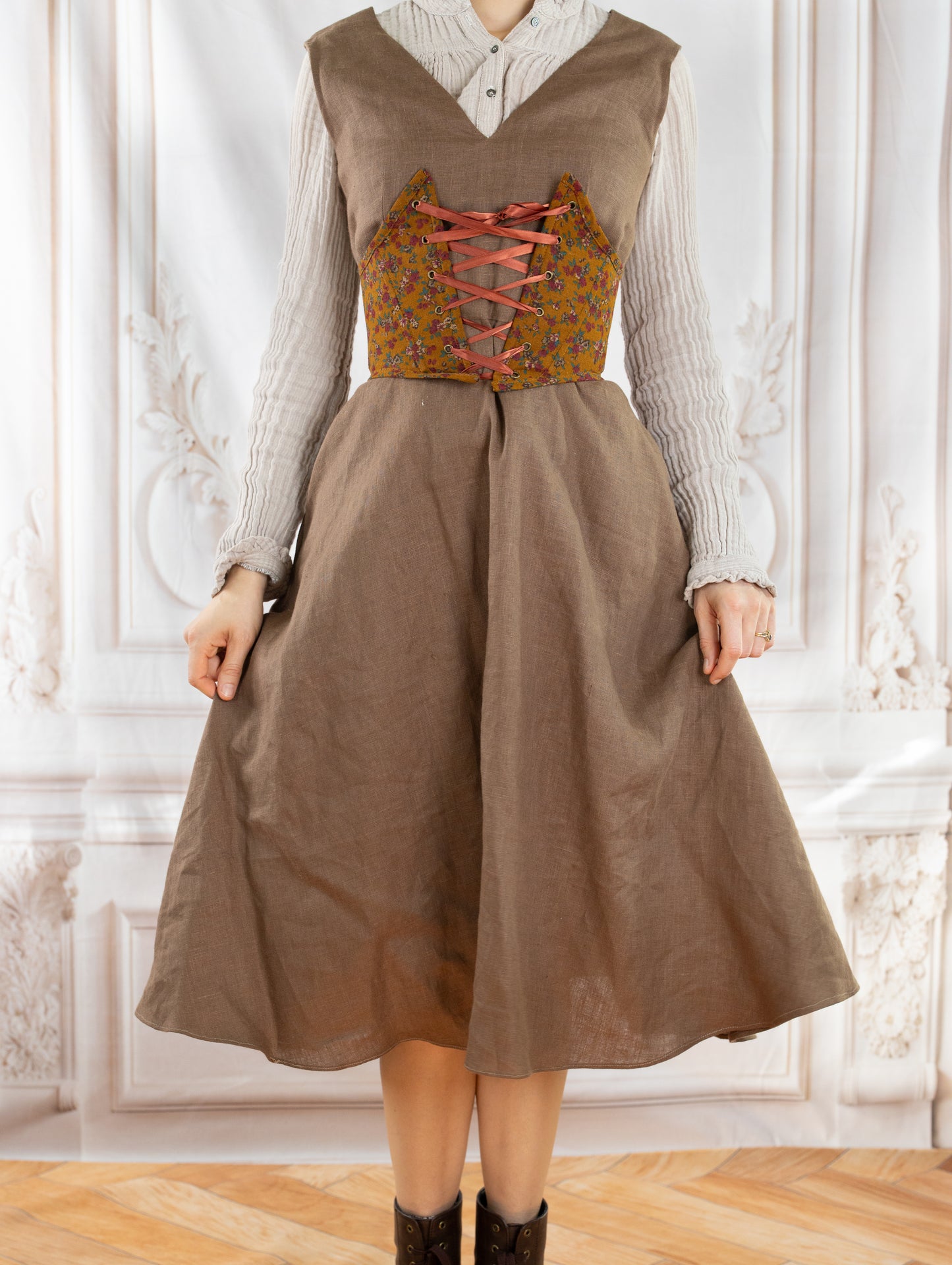Woman wearing a brown dress and floral Corset Belt PDF Sewing Pattern with pink front lacing standing indoors