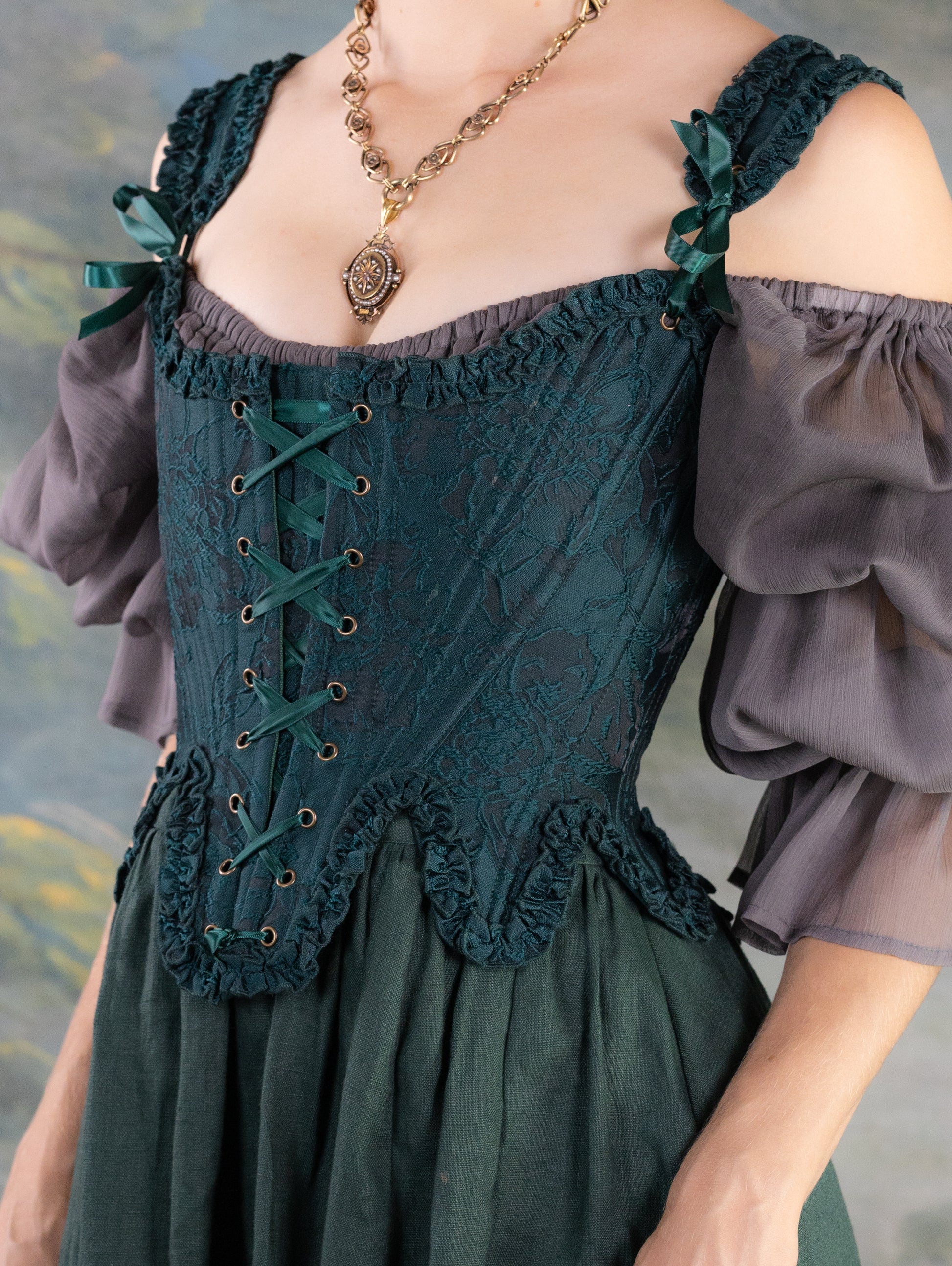 Dark Green Floral Jacquard 18th Century Stays with ruffled neckline and waistline, laced front, styled with sheer sleeves and pendant necklace