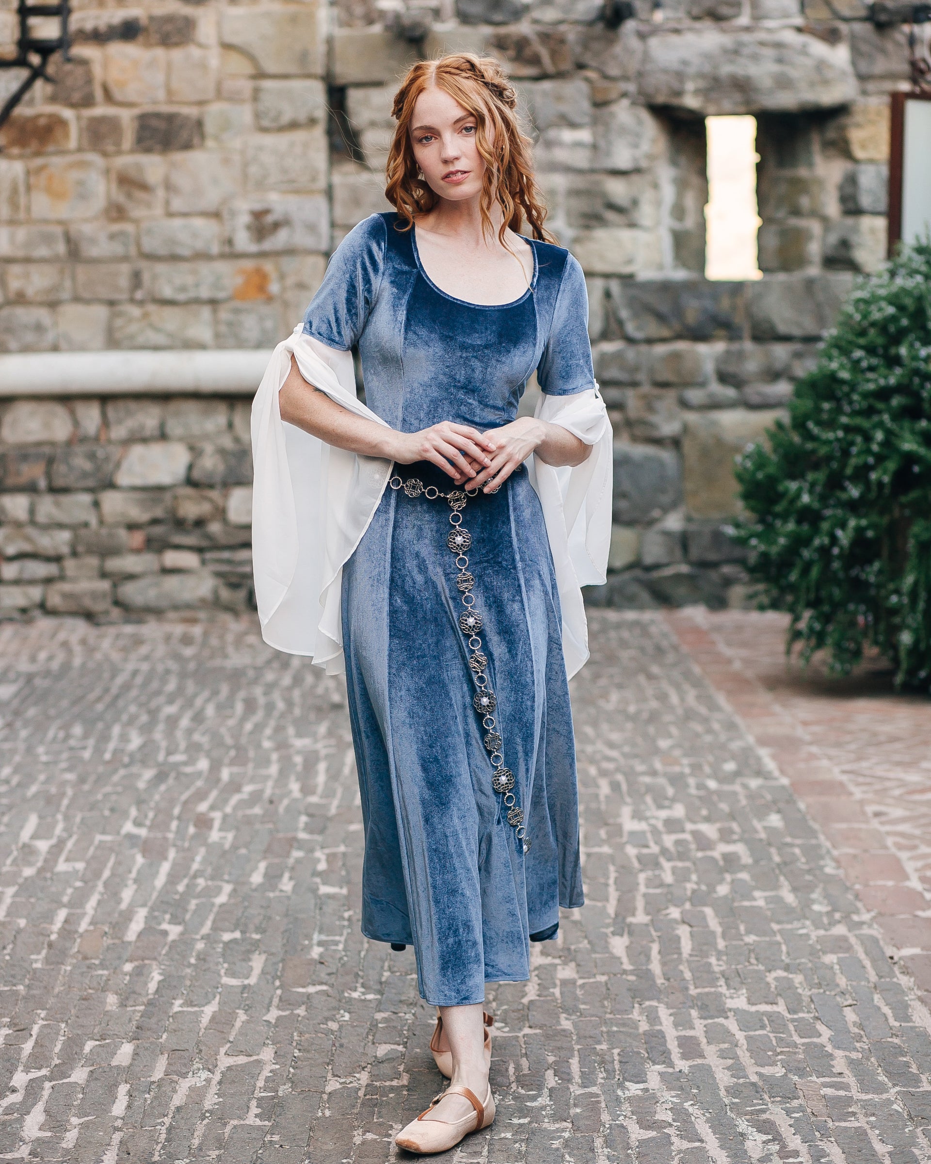 Rosette Medieval Chain Belt styled over a flowing medieval-inspired blue velvet dress with filigree rosette medallions detail