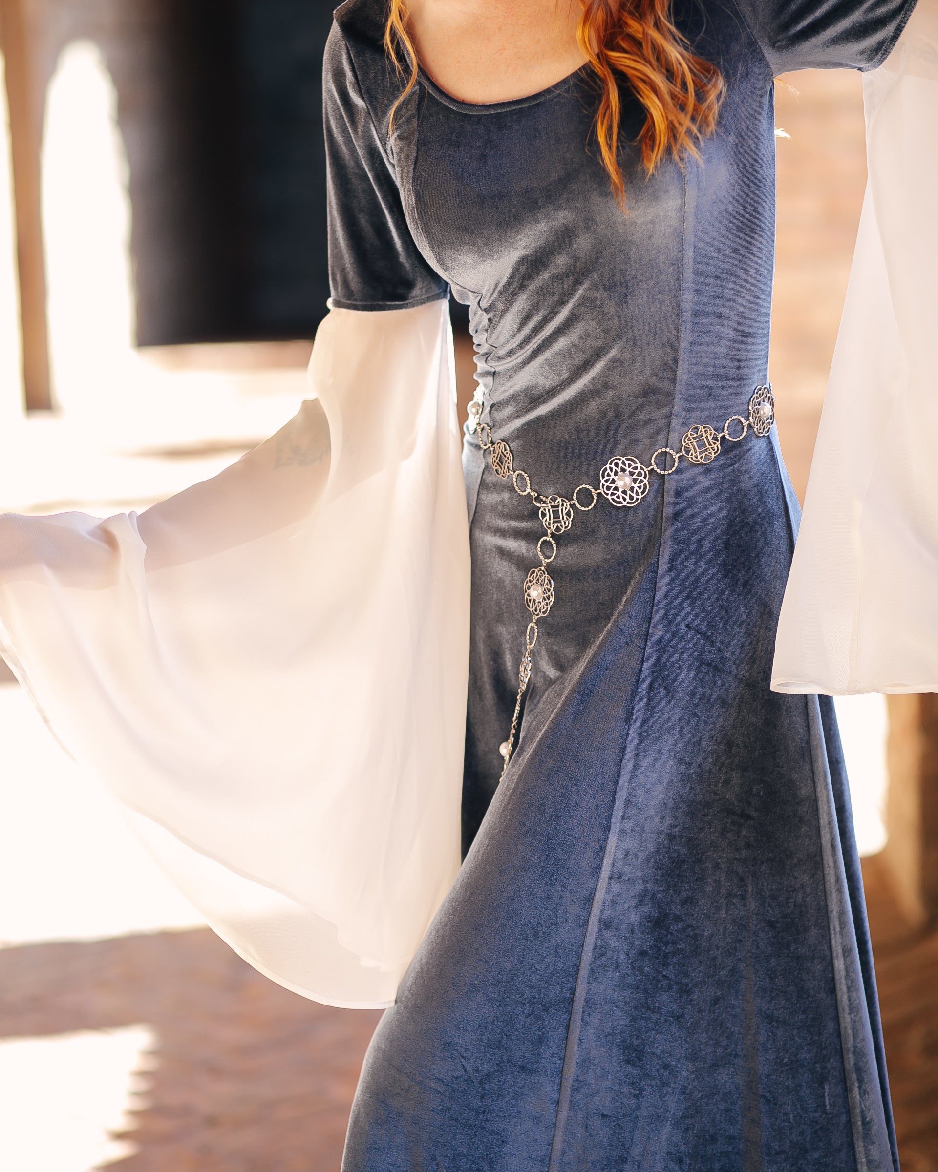 Rosette Medieval Chain Belt styled on a blue medieval dress with flowing white sleeves in natural light