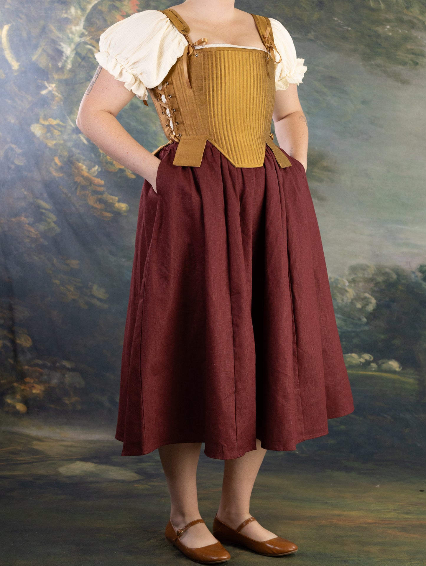 Woman wearing Gold Tabbed Tudor Stays with adjustable lacing and decorative square waist tabs over period dress