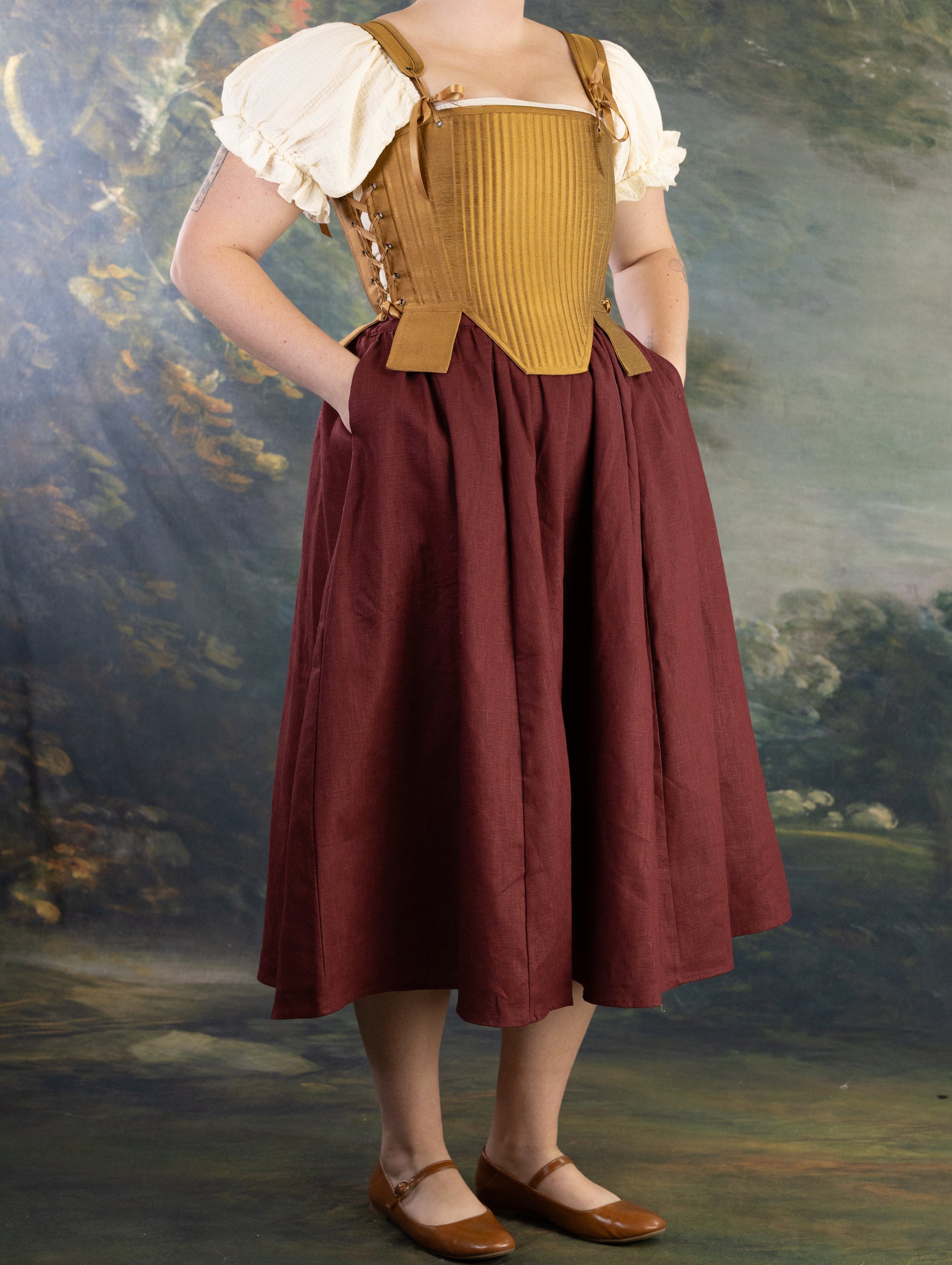 Woman wearing Gold Tabbed Tudor Stays with adjustable lacing and decorative square waist tabs over period dress