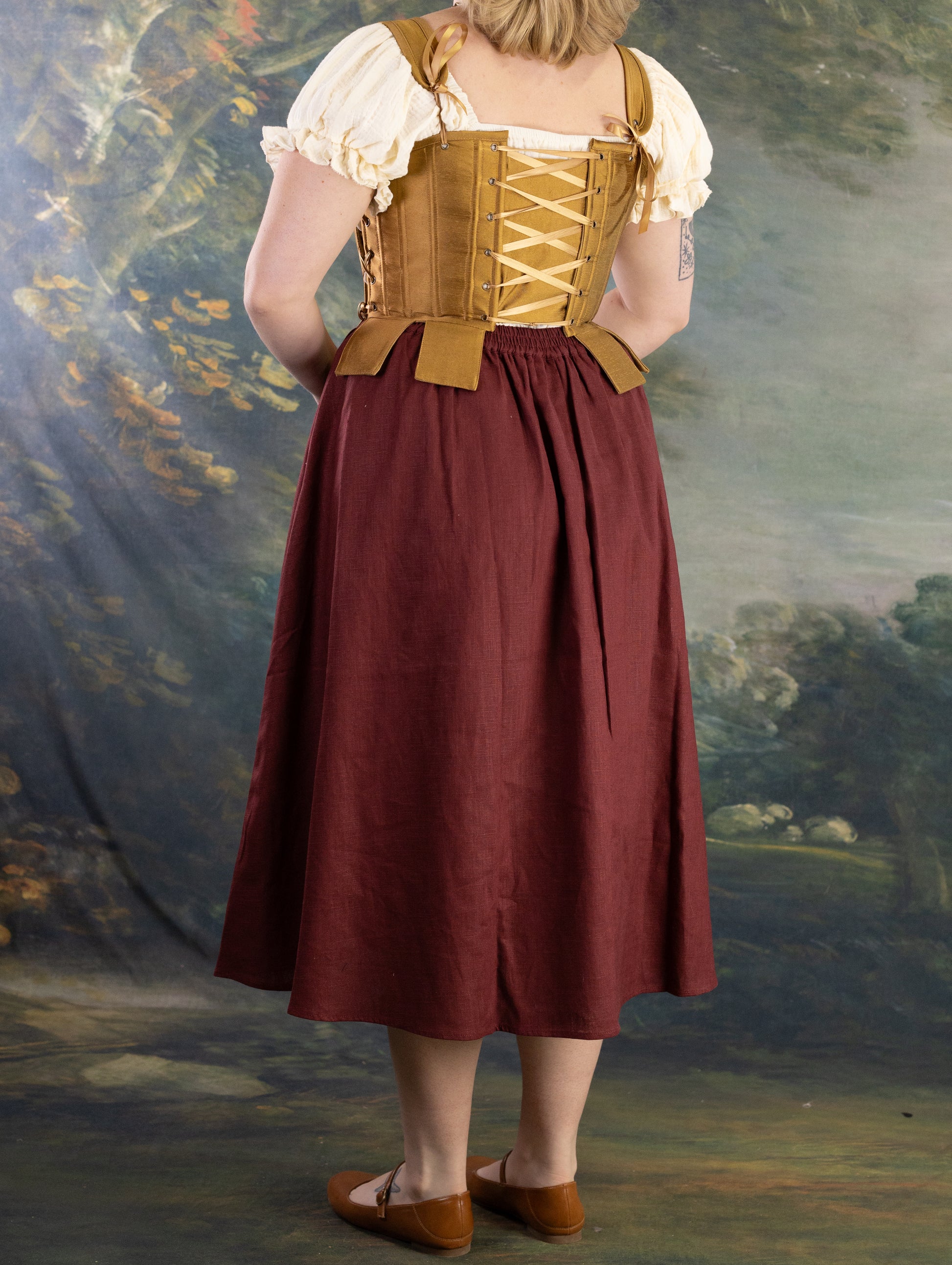 Back view of Gold Tabbed Tudor Stays with adjustable lacing worn over cream blouse and burgundy skirt in studio setting