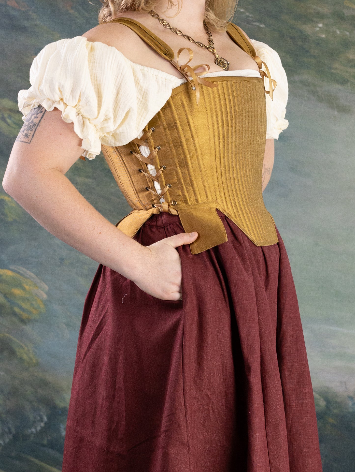 Gold Tabbed Tudor Stays shown on model, featuring adjustable side lacing and decorative square waist tabs in mustard gold tone.