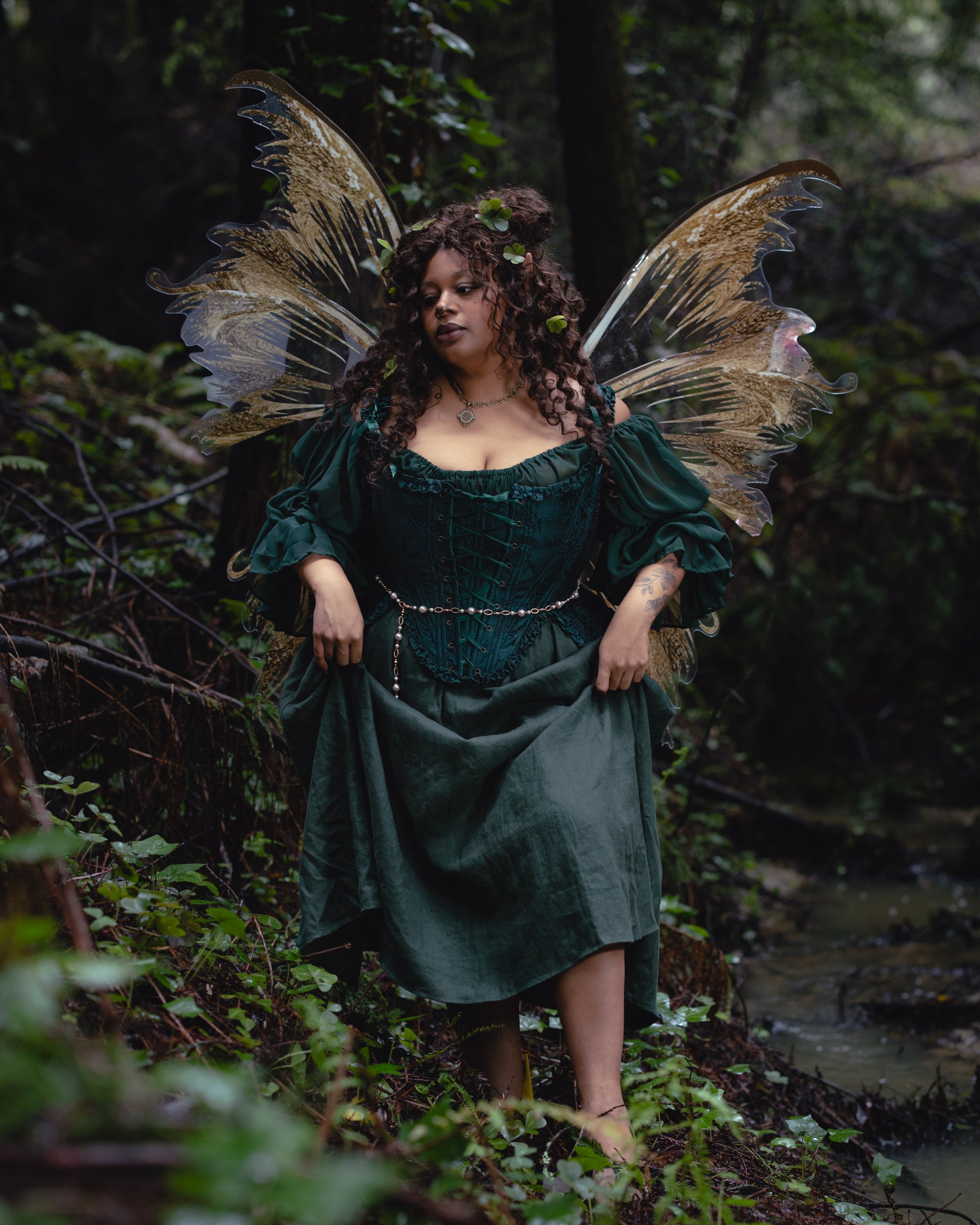 Woman dressed in Dark Green Floral Jacquard 18th Century Stays with fairy wings standing in a forest setting