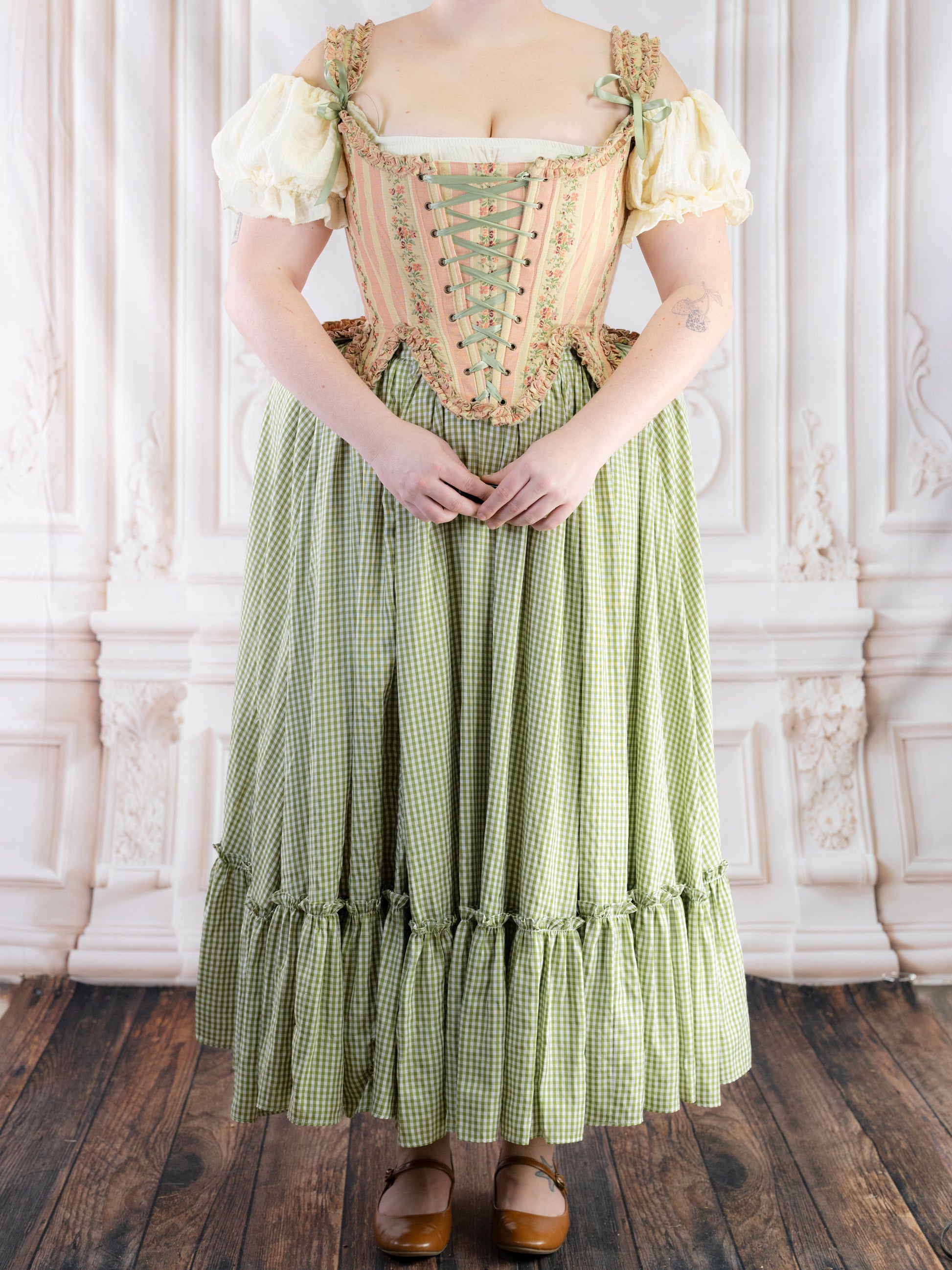 Woman wearing a vintage style dress with a Green Gingham Ruffle Skirt standing on wooden floor in ornate room