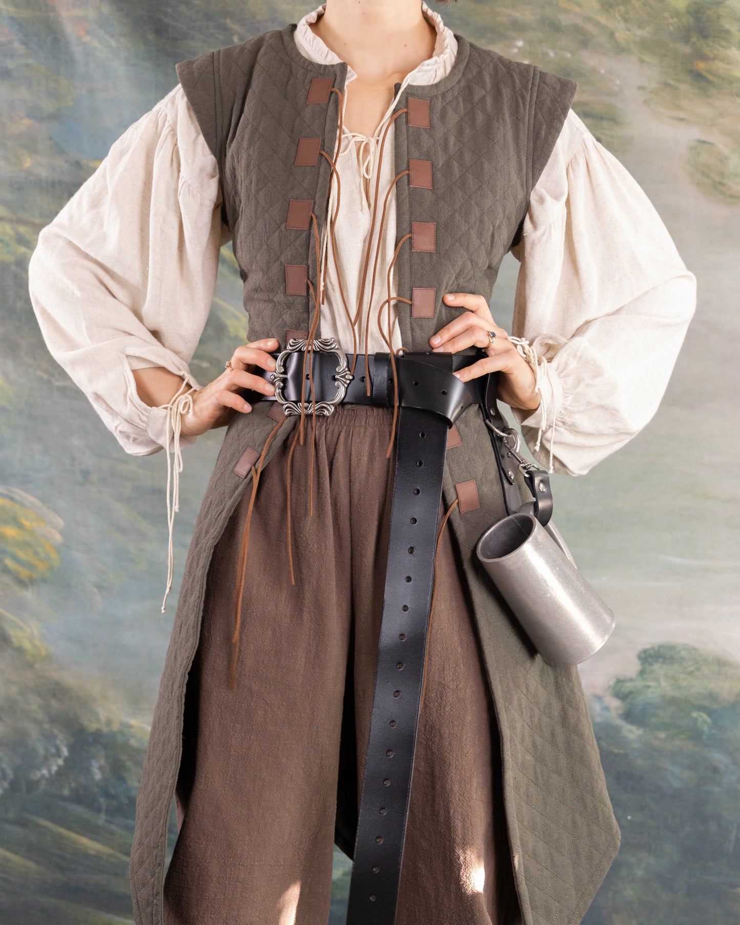 Woman wearing a historically inspired quilted gambeson with leather belt and medieval-style blouse and pants