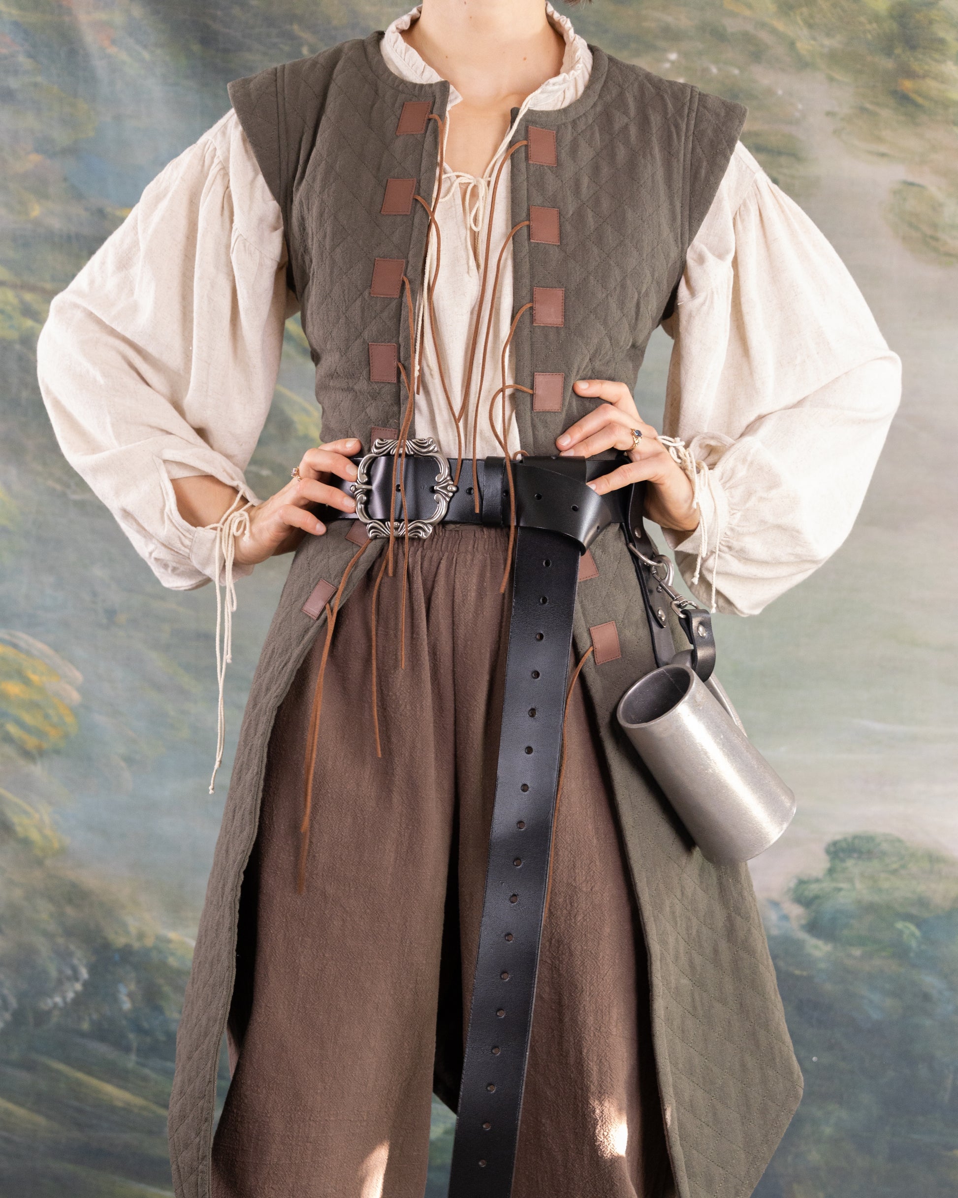 Woman wearing a historically inspired quilted gambeson with leather belt and medieval-style blouse and pants