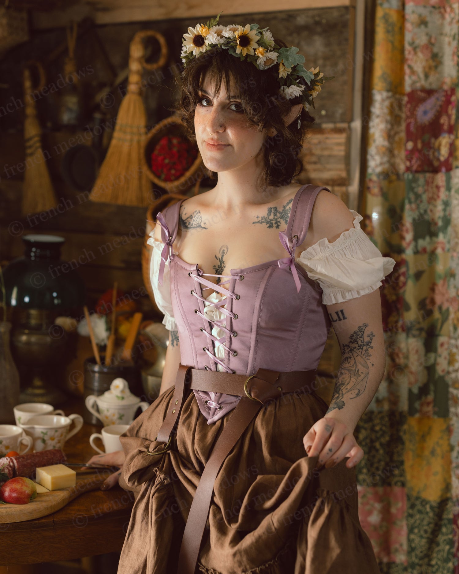 Purple Dusk Satin Corset Top styled with brown skirt and white daisy crown in rustic cottage setting with vintage tea service