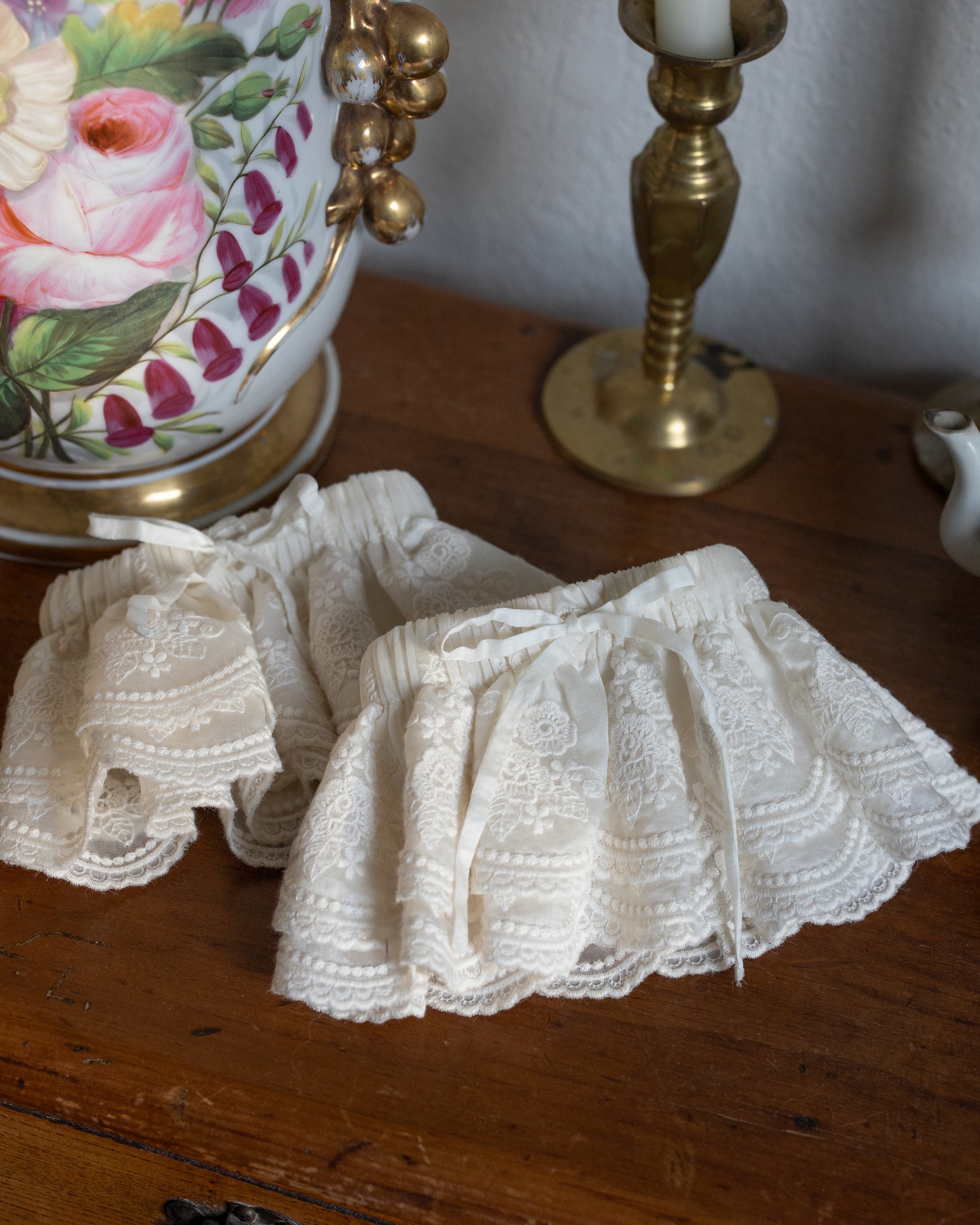 Lacey Ruffle Sleeves in delicate lace with intricate patterns displayed on a wooden surface next to vintage decor.