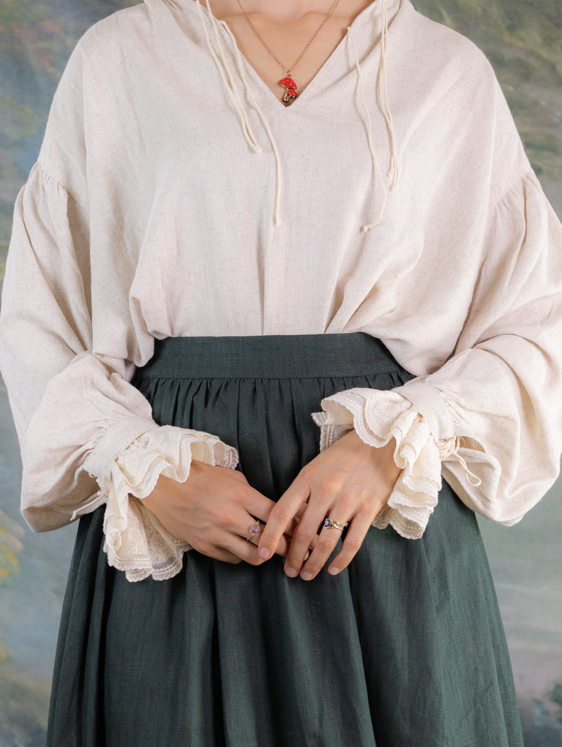Woman wearing vintage style blouse with Lacey Ruffle Sleeves paired with a dark skirt and layered rings on fingers