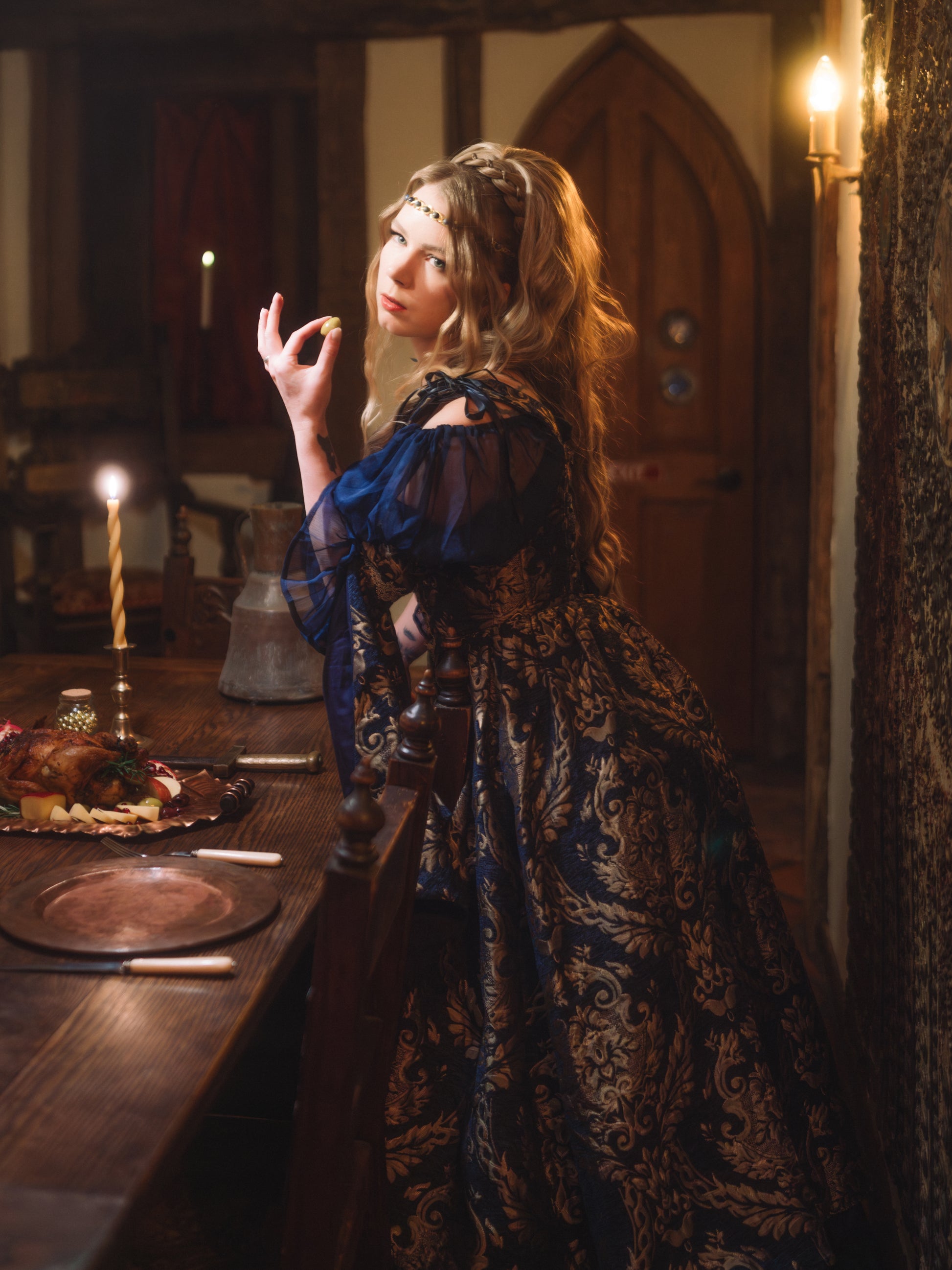 Woman in a medieval setting wearing a Navy Blue Chenille Corset Dress with gold accents by candlelight