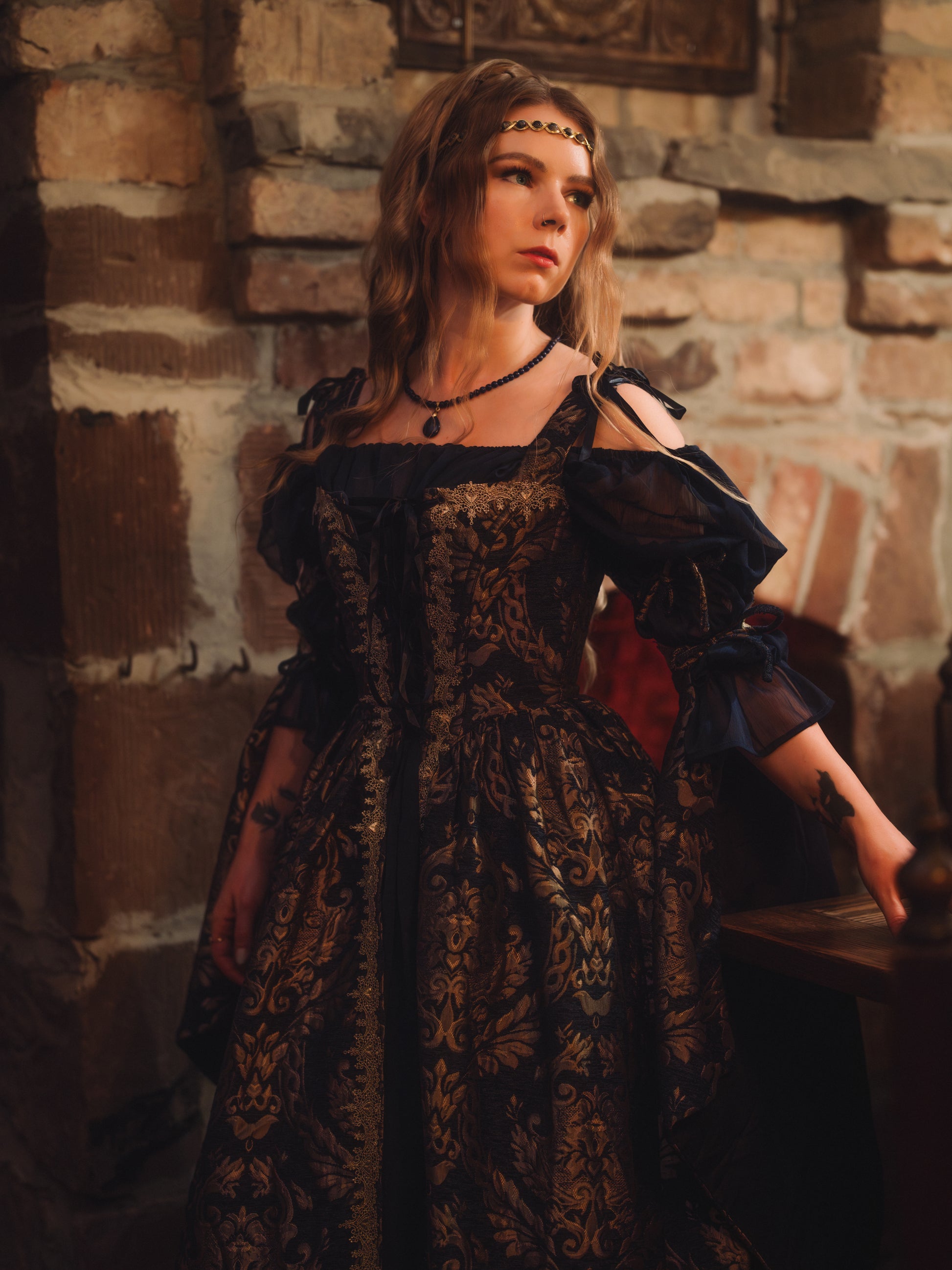 Woman wearing a Navy Blue Chenille Corset Dress with gold accents in a medieval stone room setting